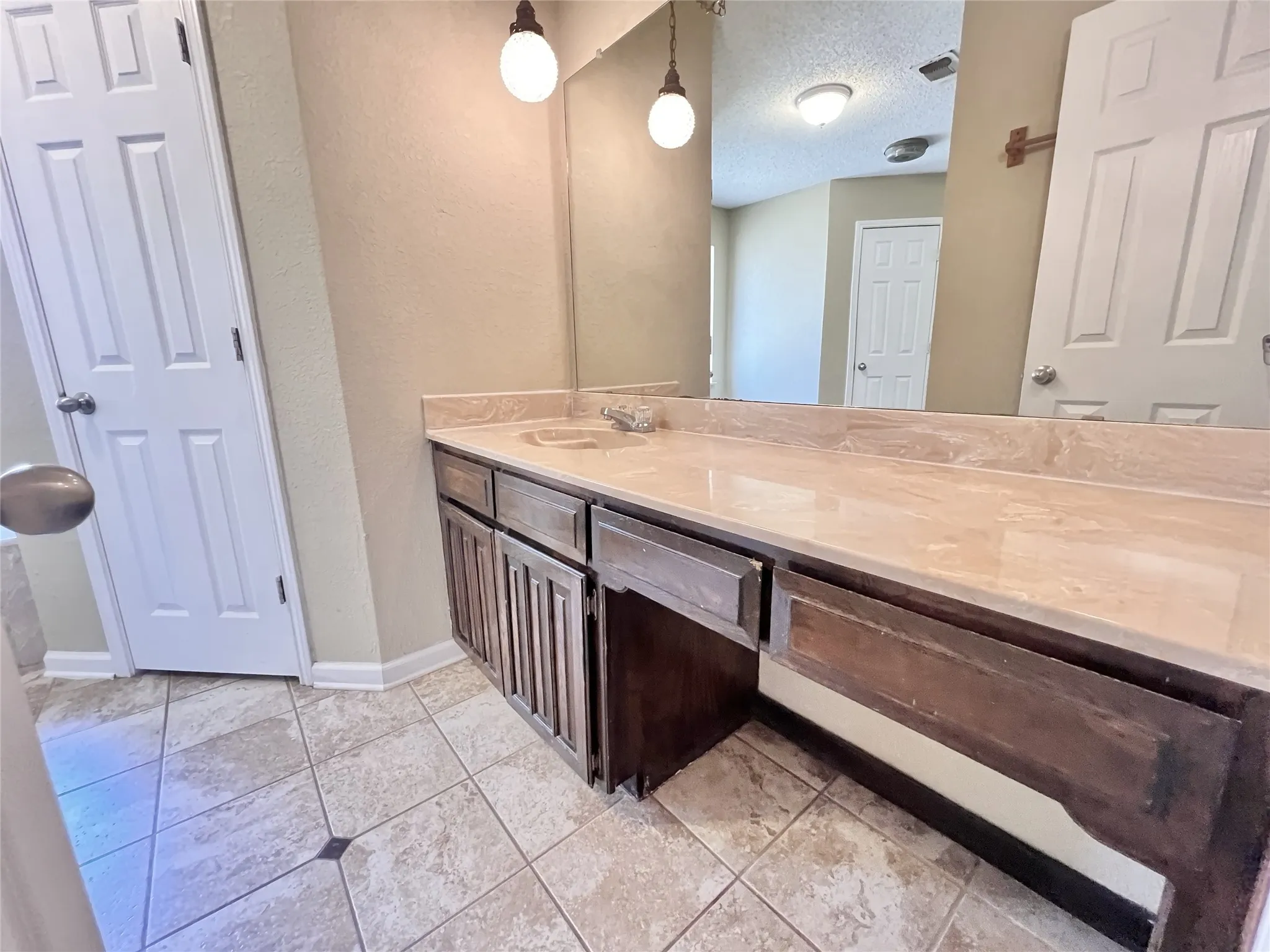 Integrated vanity with a polished countertop, recessed sink, and dark wood-finish cabinetry. These pictures are prior to the current tenant moving in.