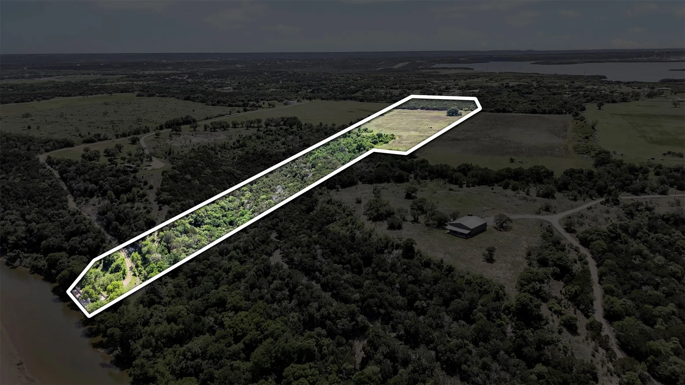 Aerial depiction of a substantial land parcel, outlined in white, featuring a diverse landscape