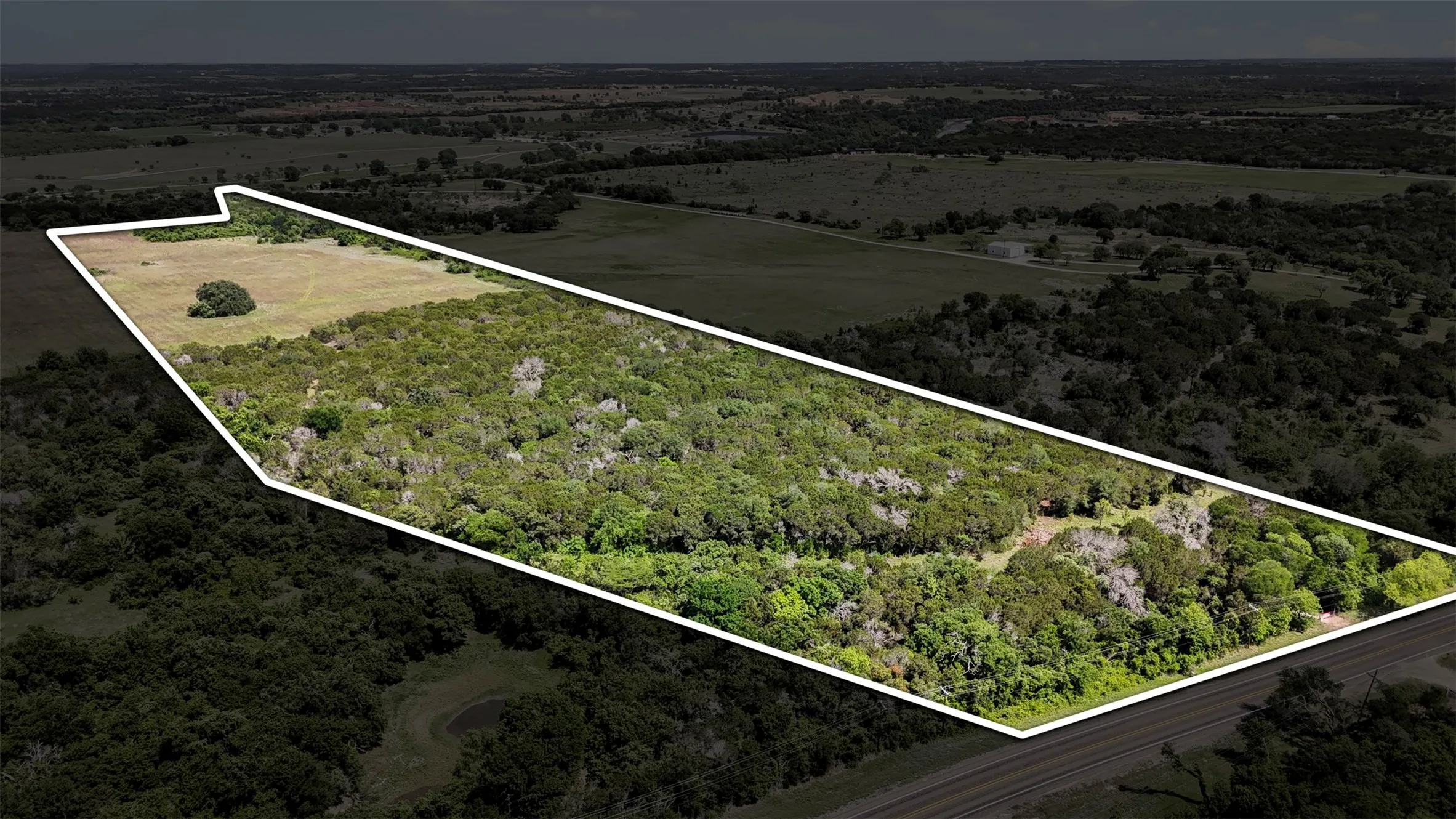 Expansive land parcel featuring diverse topography with both open fields and dense tree coverage
