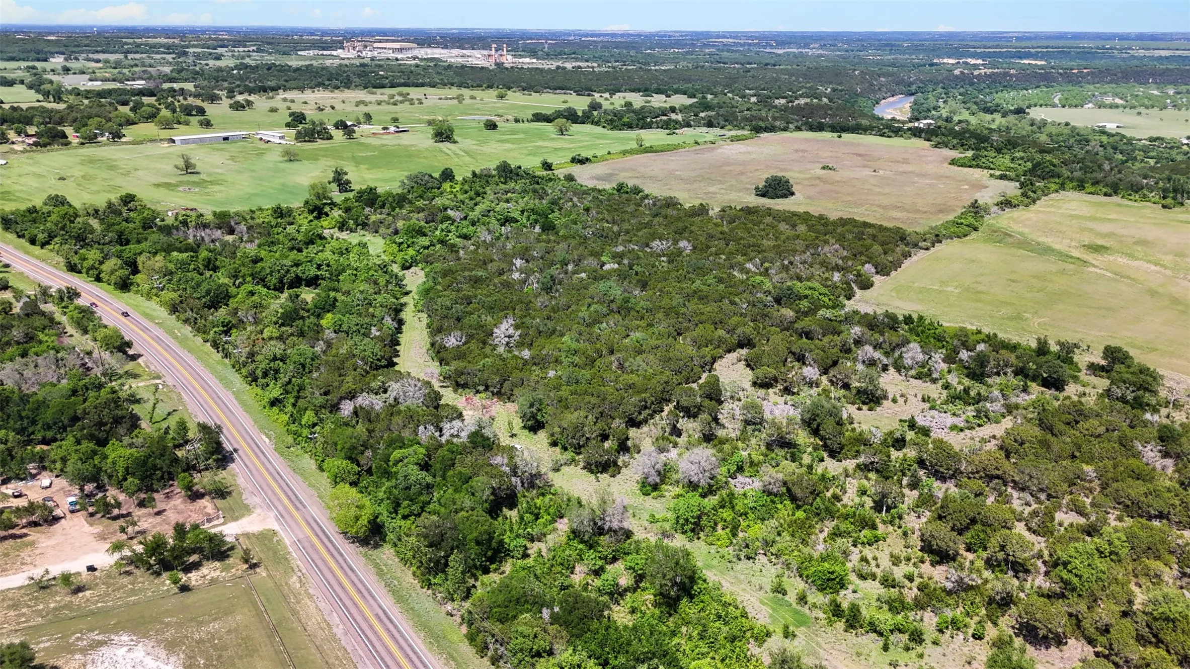 Expansive landscape featuring diverse tree coverage, open grassy areas, and a visible roadway