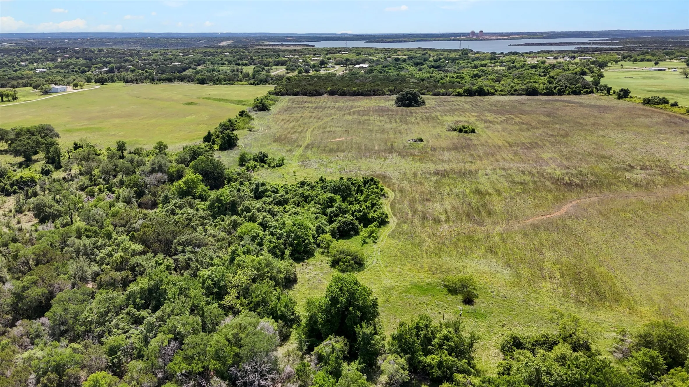Expansive land parcel featuring a mix of open fields and dense tree coverage