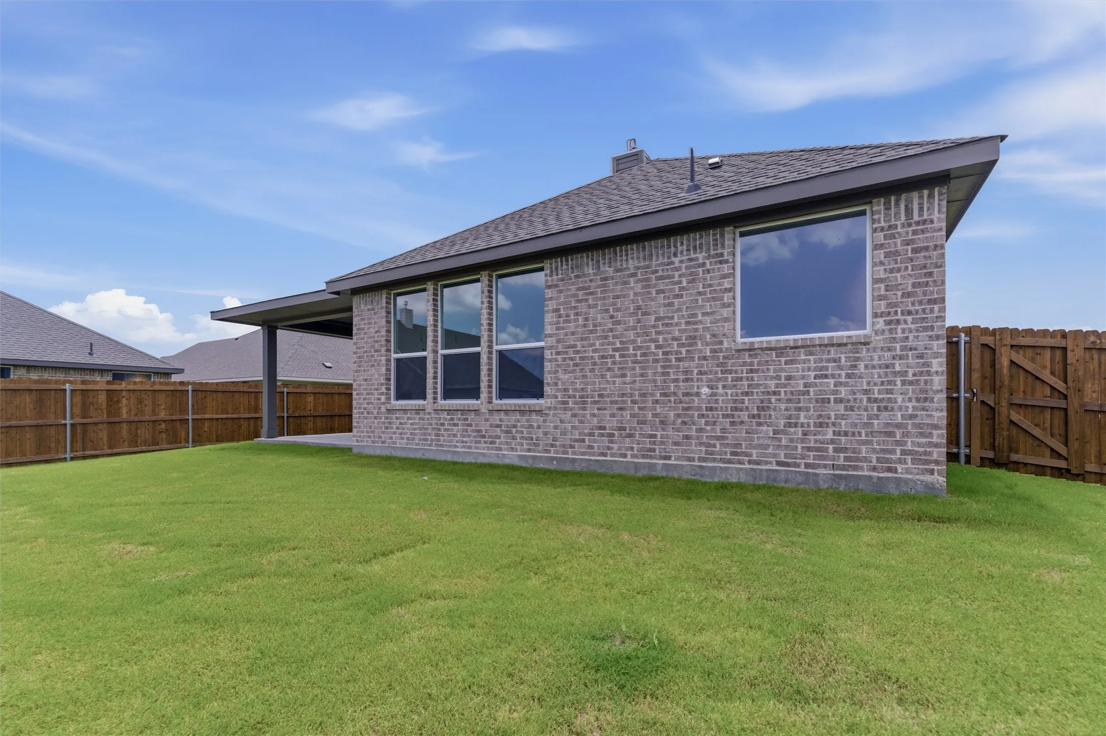 Expansive backyard featuring a manicured lawn, a covered patio, and a privacy fence