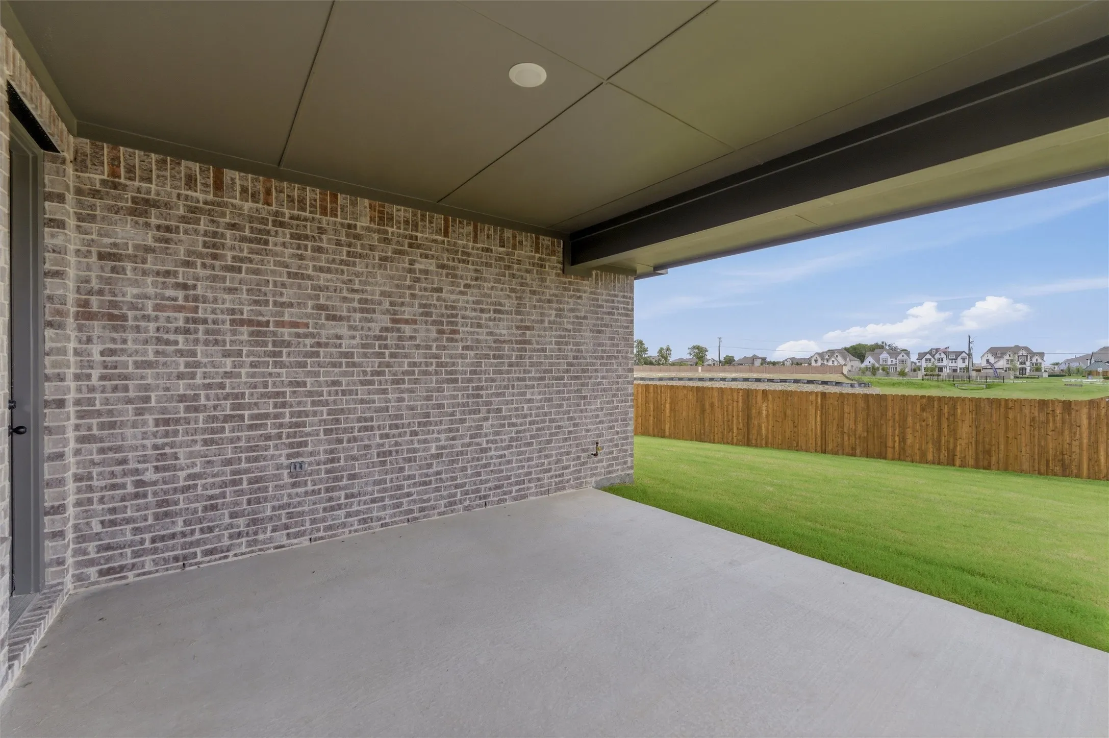 Covered patio featuring a concrete slab and a brick exterior wall