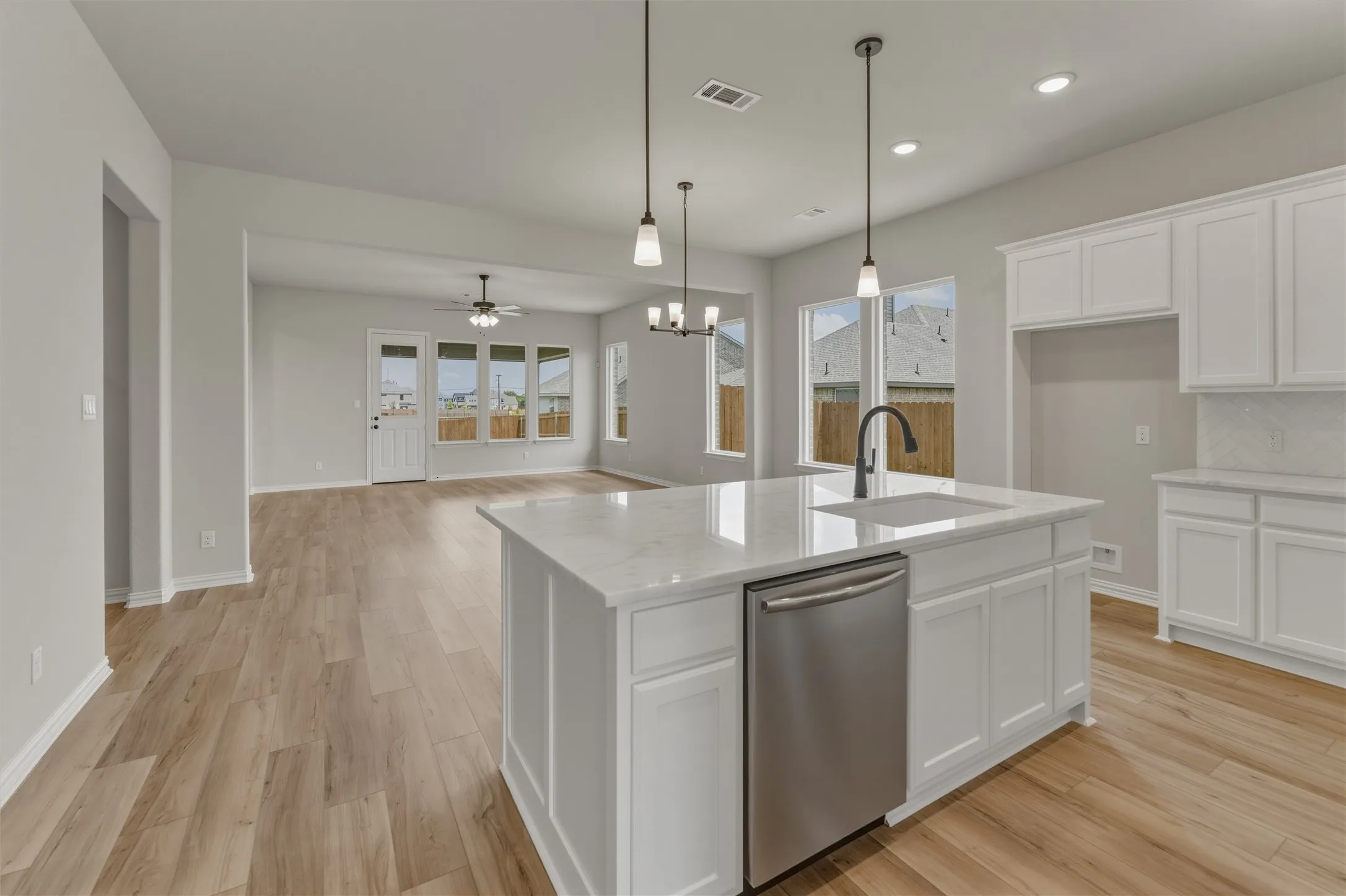Kitchen island featuring a white countertop, undermount sink with a black gooseneck faucet, and a stainless steel dishwasher