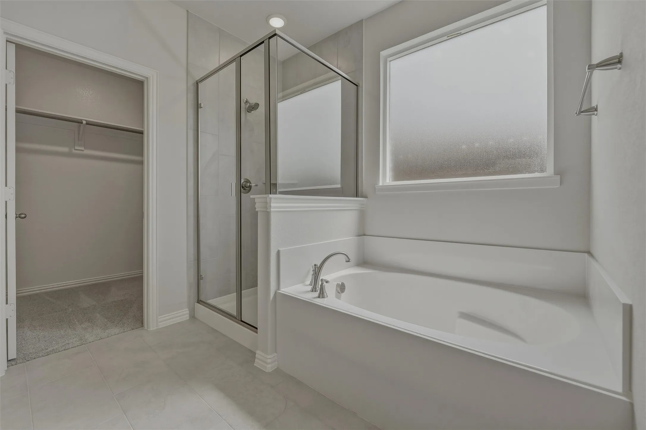 Built-in soaking tub, glass-enclosed shower, tiled shower surround, recessed lighting, and frosted window