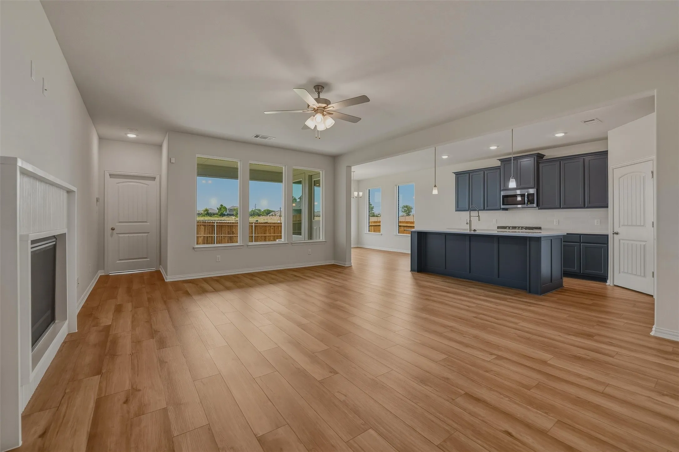 Expansive open-concept living area featuring wood-finish flooring, recessed lighting, and a ceiling fan