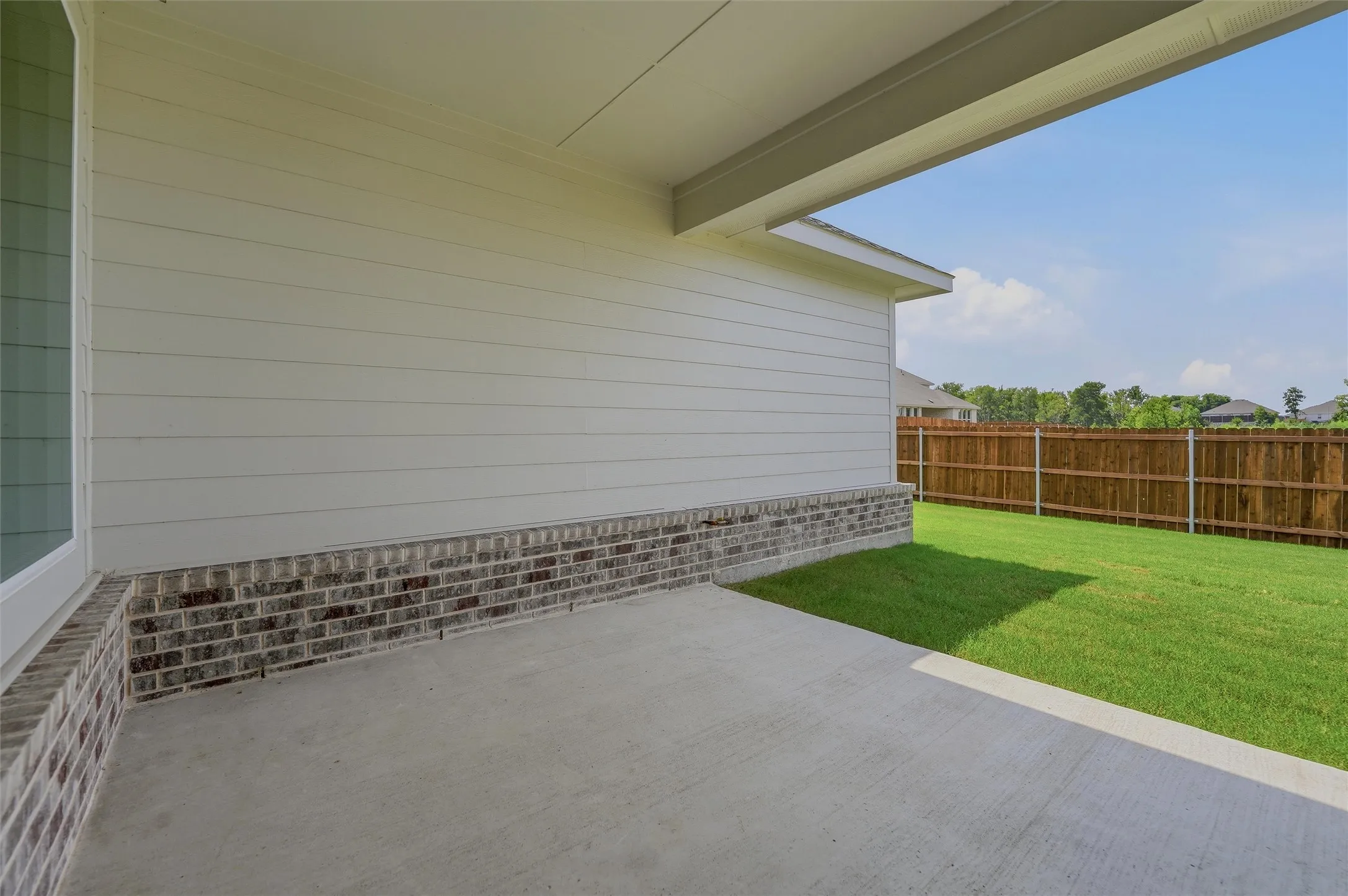 Expansive outdoor patio with concrete flooring, covered ceiling, and brick and siding exterior