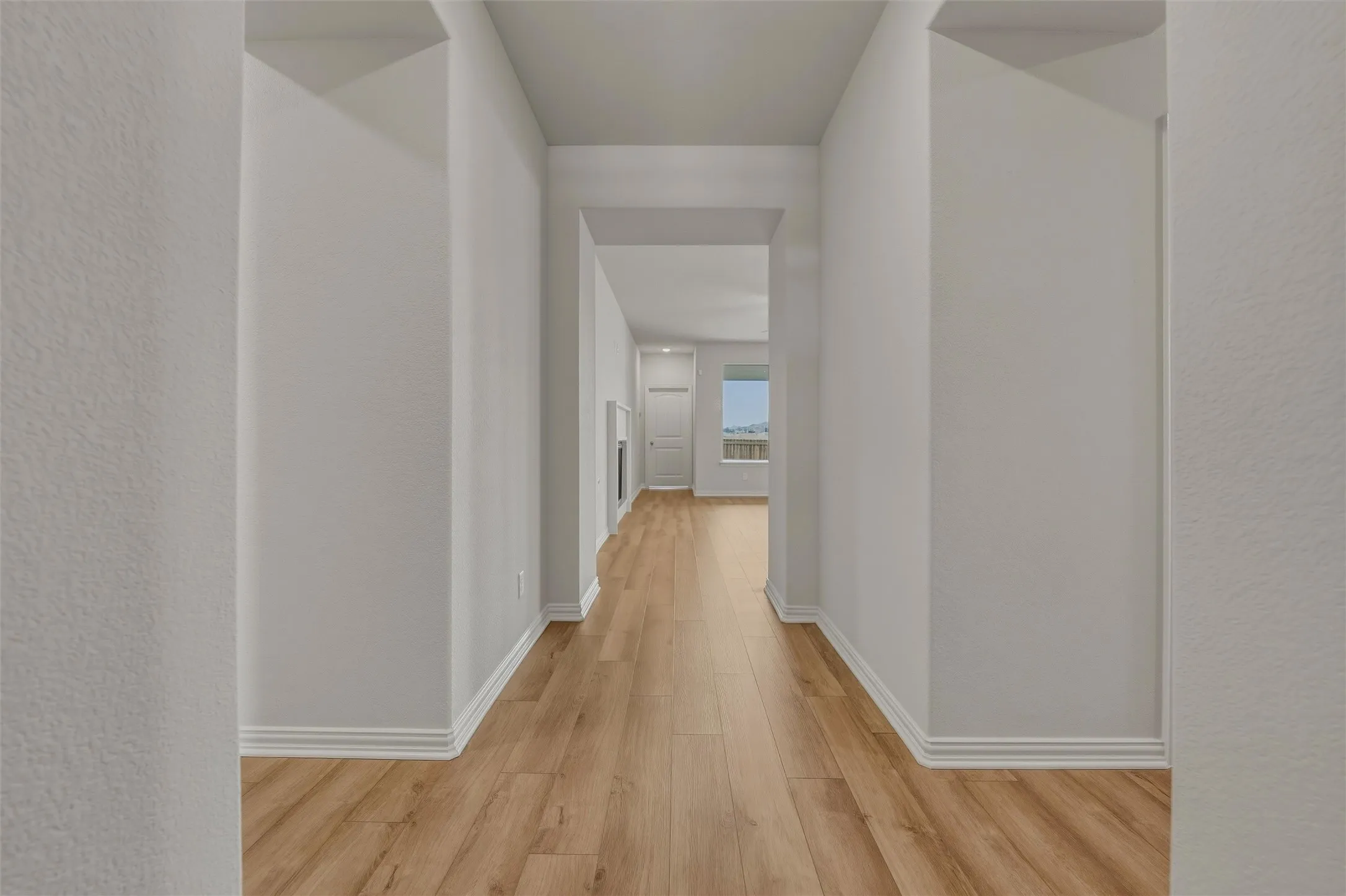 Hallway featuring wood-finish flooring, light-toned walls, and white trim