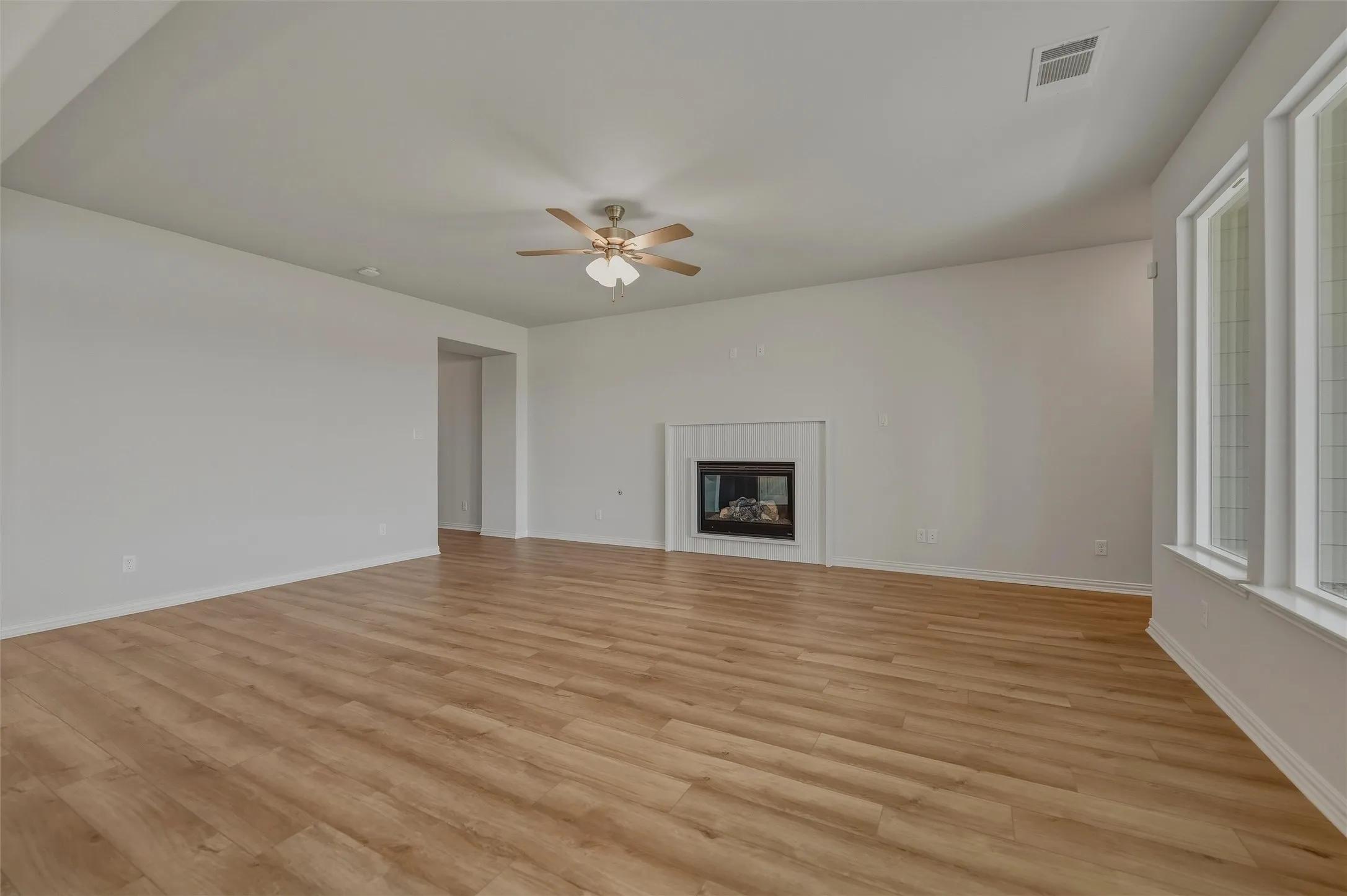 Wood-finish flooring throughout, multiple windows, and a built-in fireplace with a mantel