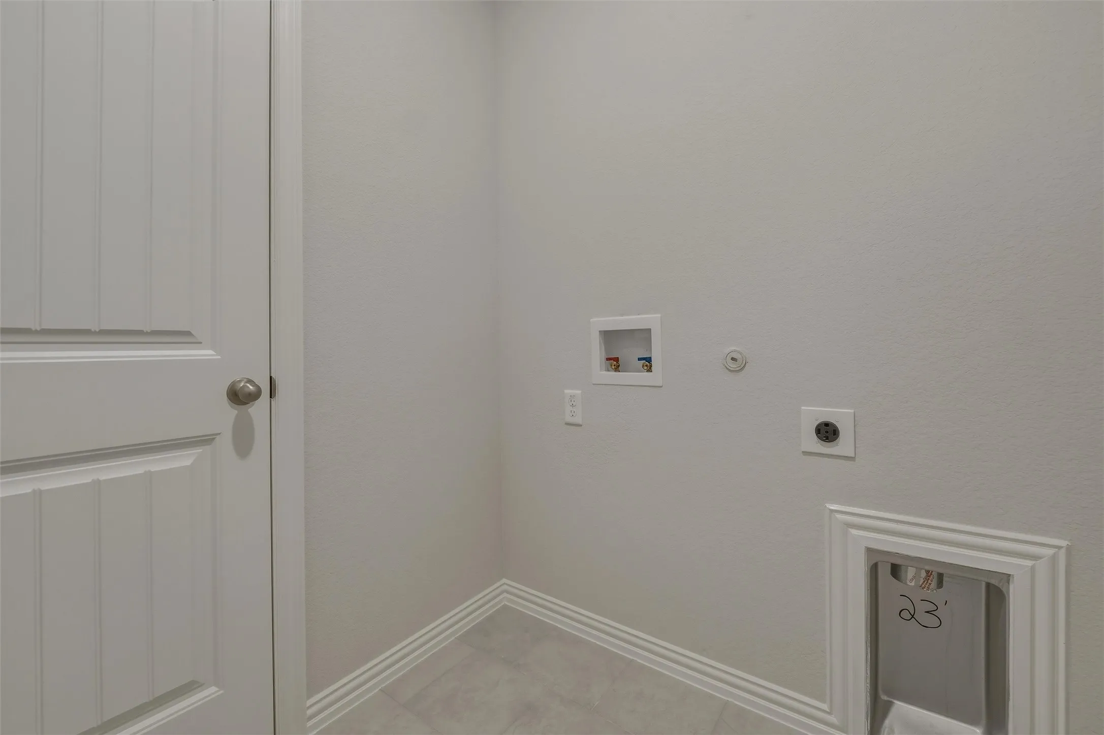 Utility connections with a drain, electrical outlet, water hookups, and a paneled door
