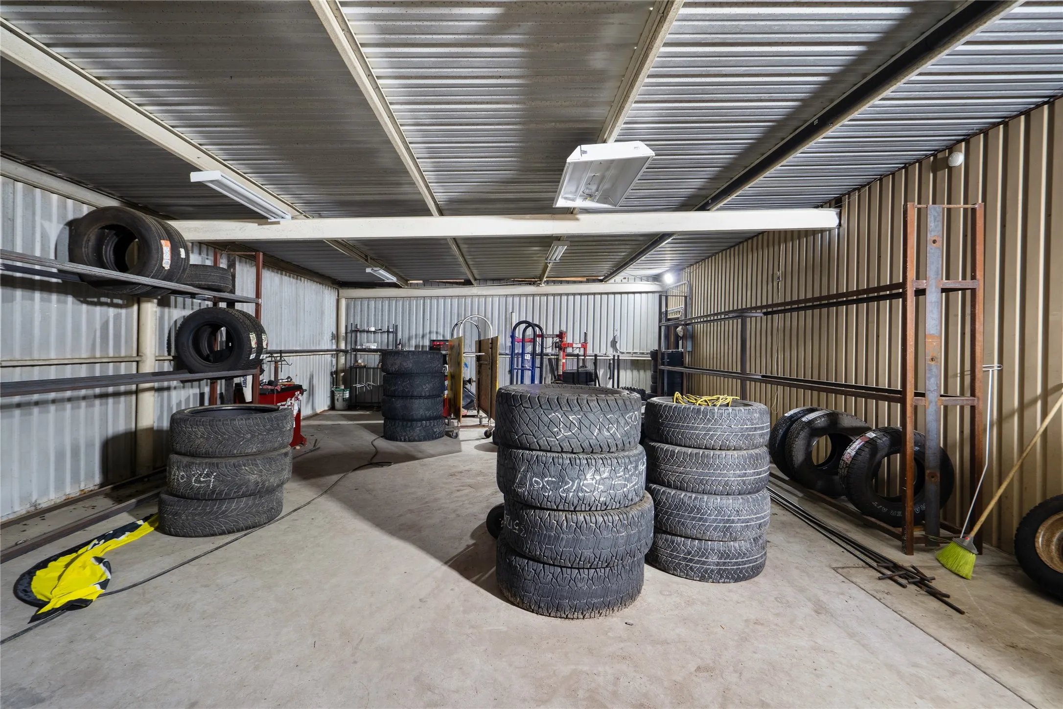 Utility room featuring corrugated metal walls and ceiling, concrete flooring, and fluorescent lighting fixtures