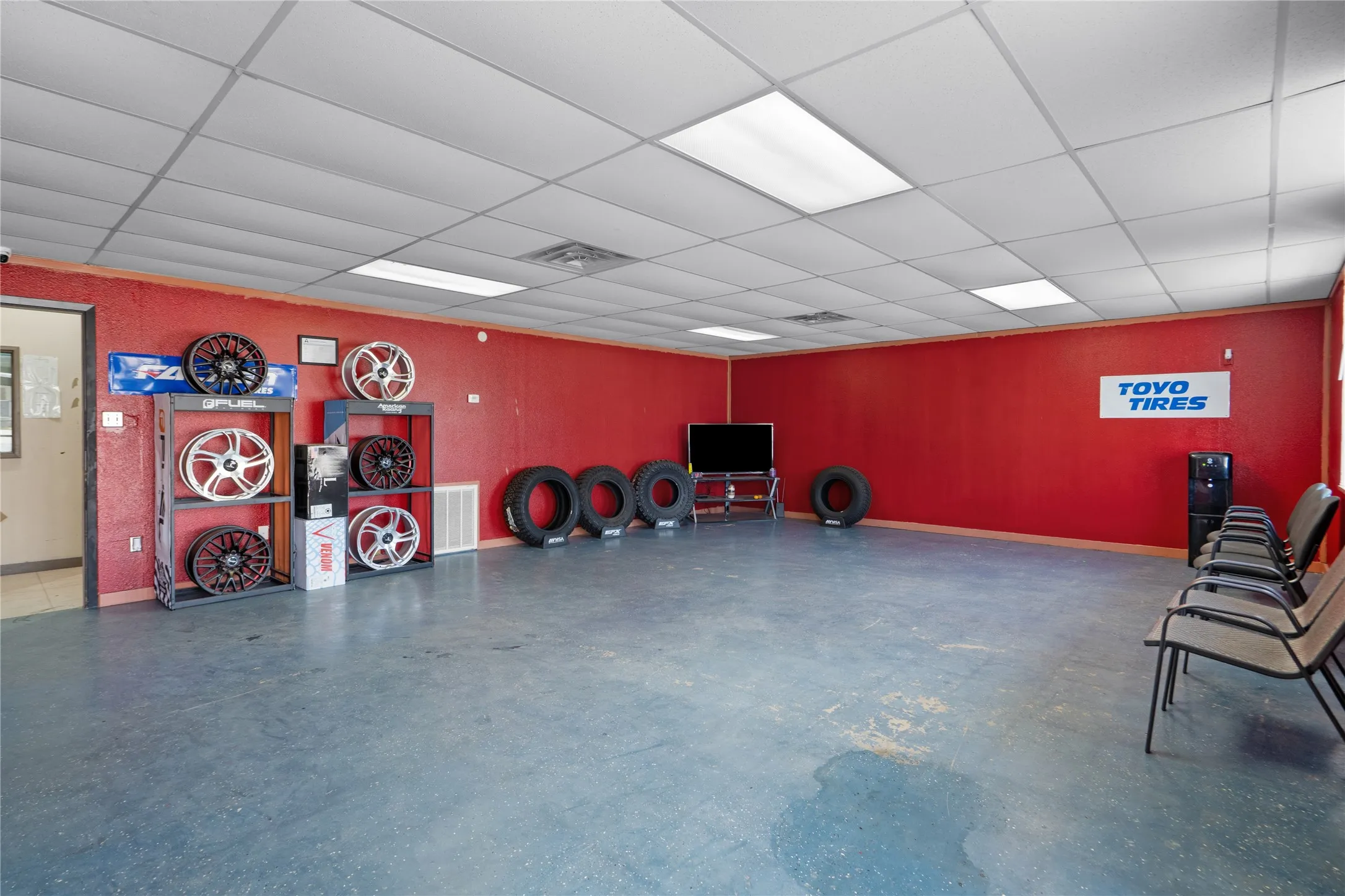 Spacious commercial interior with textured red walls, drop ceiling with integrated lighting, and blue-toned​​‌​​​​‌​​‌‌​‌‌​​​‌‌​‌​‌​‌​​​‌​​ flooring