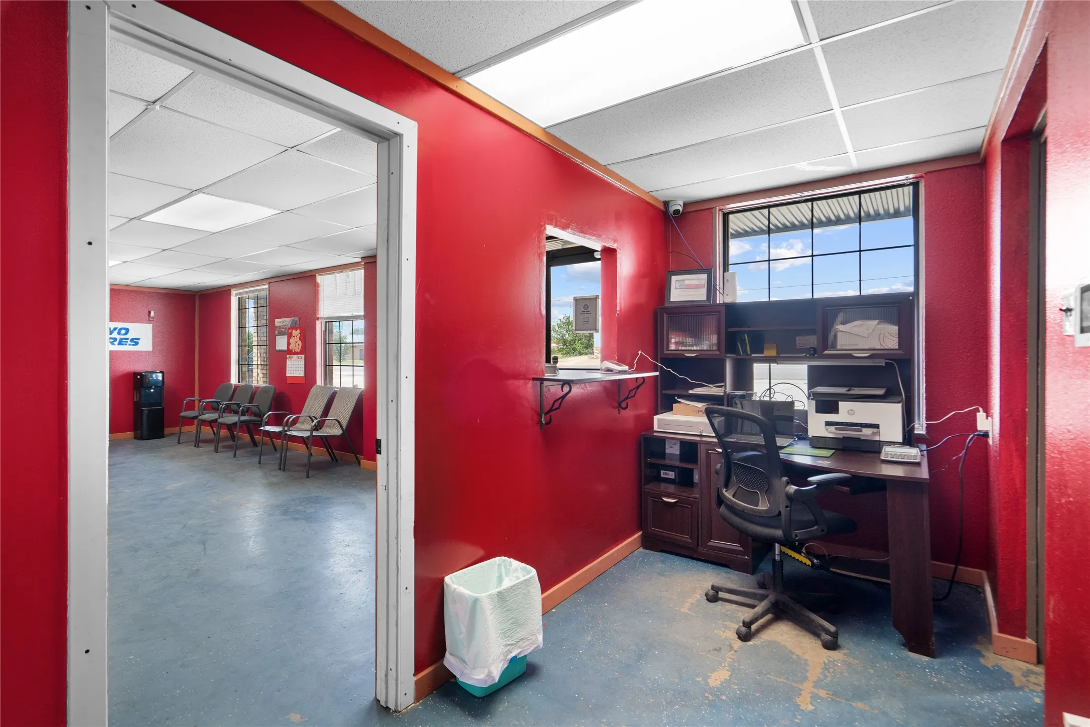 Reception area featuring a service window, drop ceiling with fluorescent lighting, and a large window