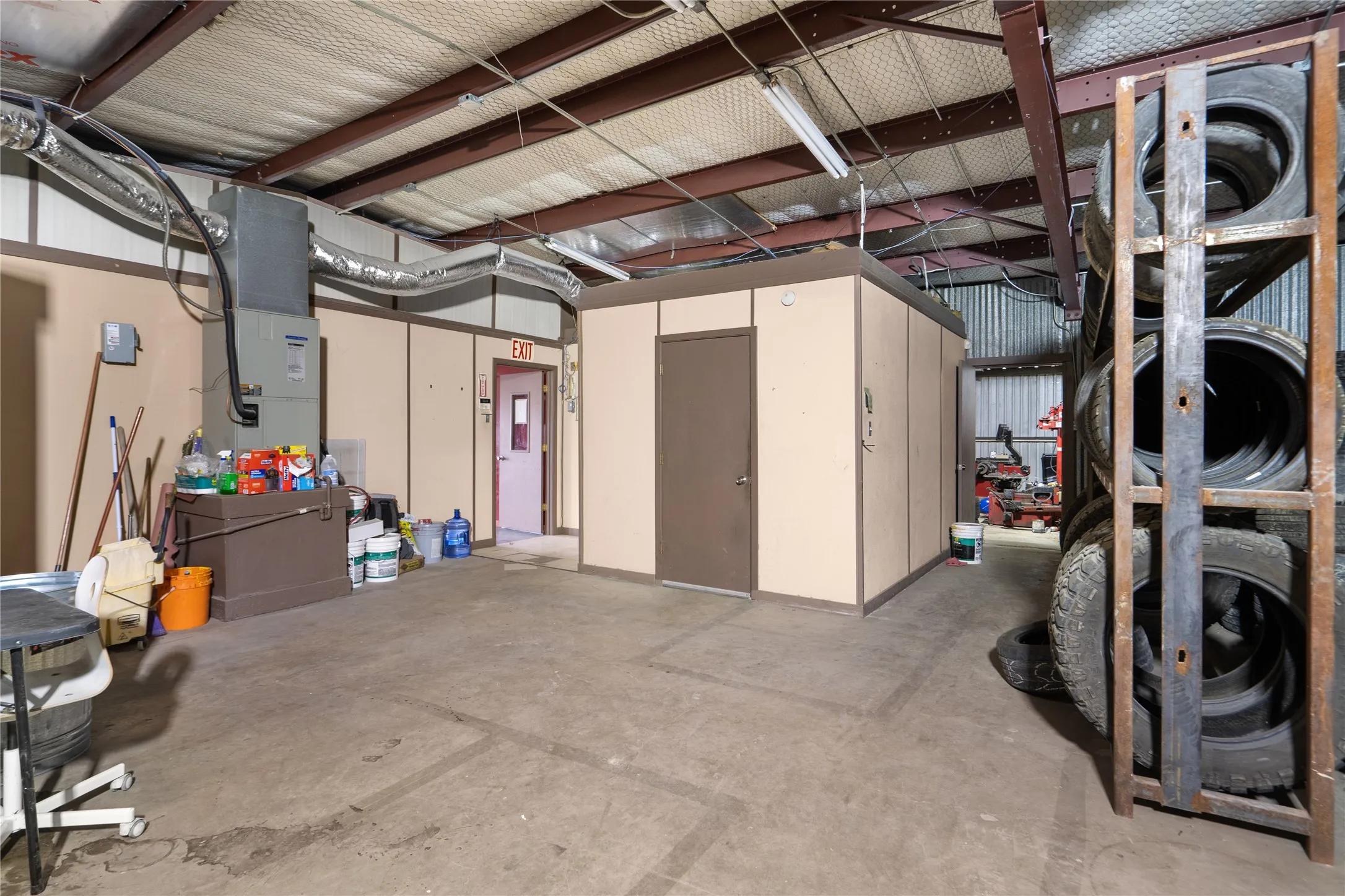 Warehouse interior featuring exposed steel beams, concrete flooring, and suspended fluorescent lighting