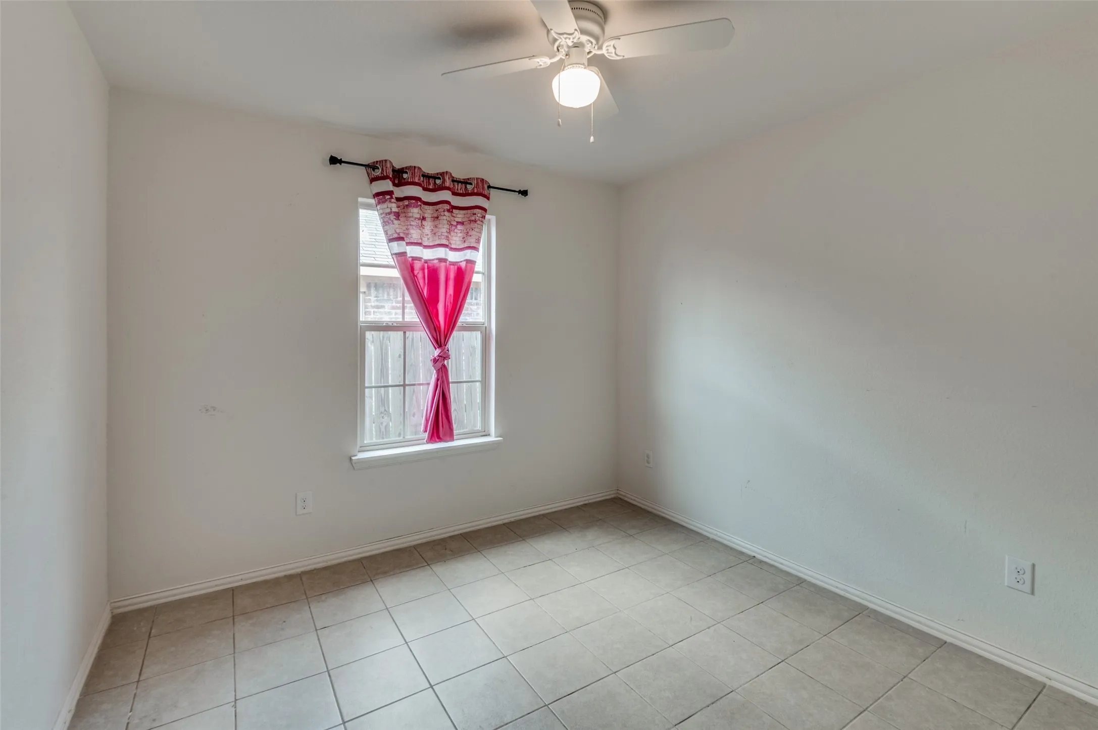 Neutral white walls with tile flooring, featuring a window with grid panes and a ceiling fan with integrated lighting