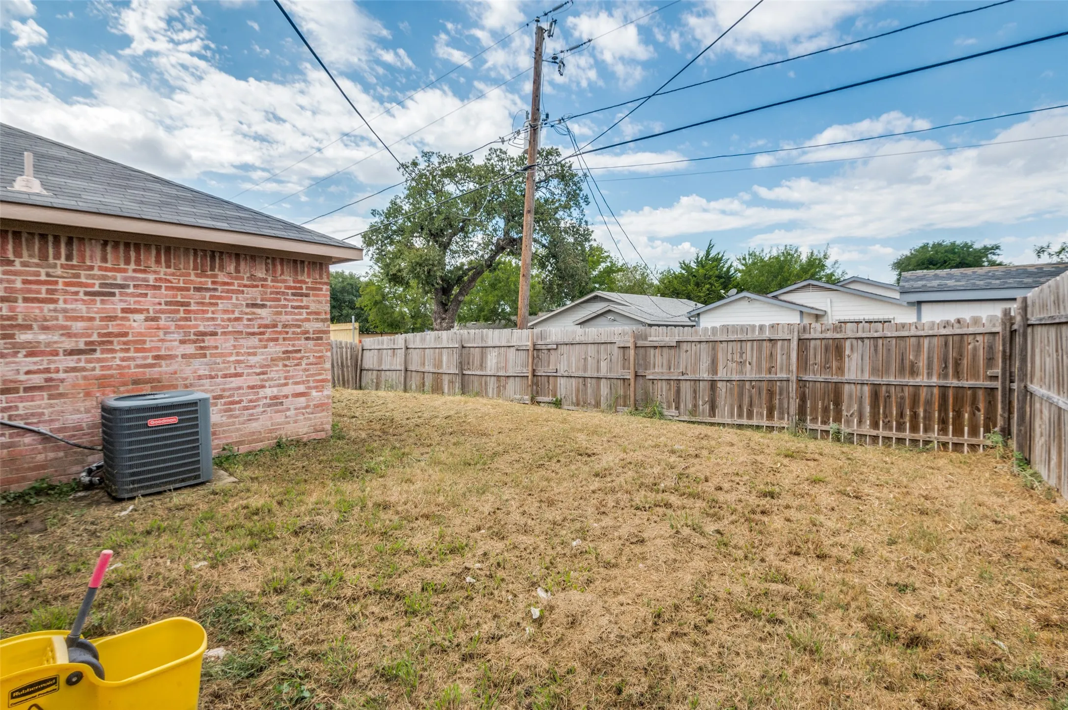 Expansive rear yard featuring a wood privacy fence and brick exterior
