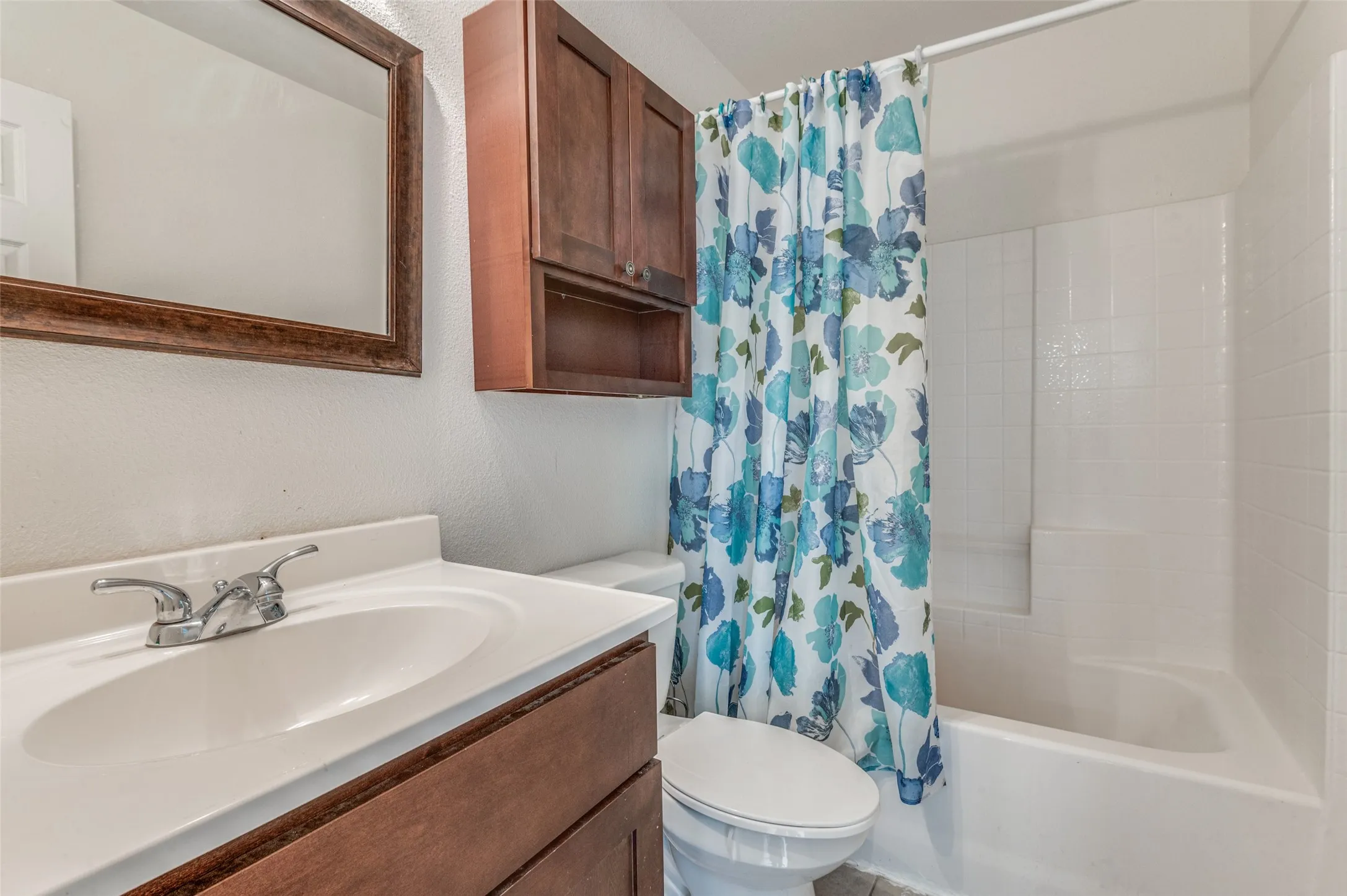 Bathroom featuring a white vanity with integrated sink, chrome faucet, and wood-finish cabinetry