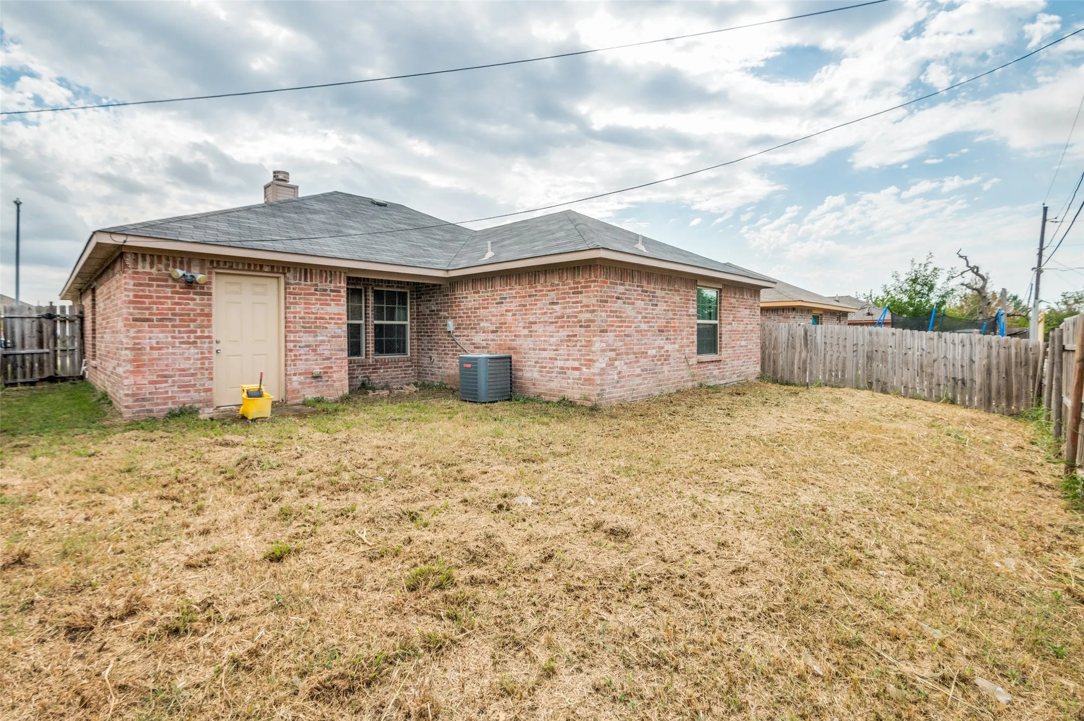 Brick exterior with a shingle roof and a fenced backyard