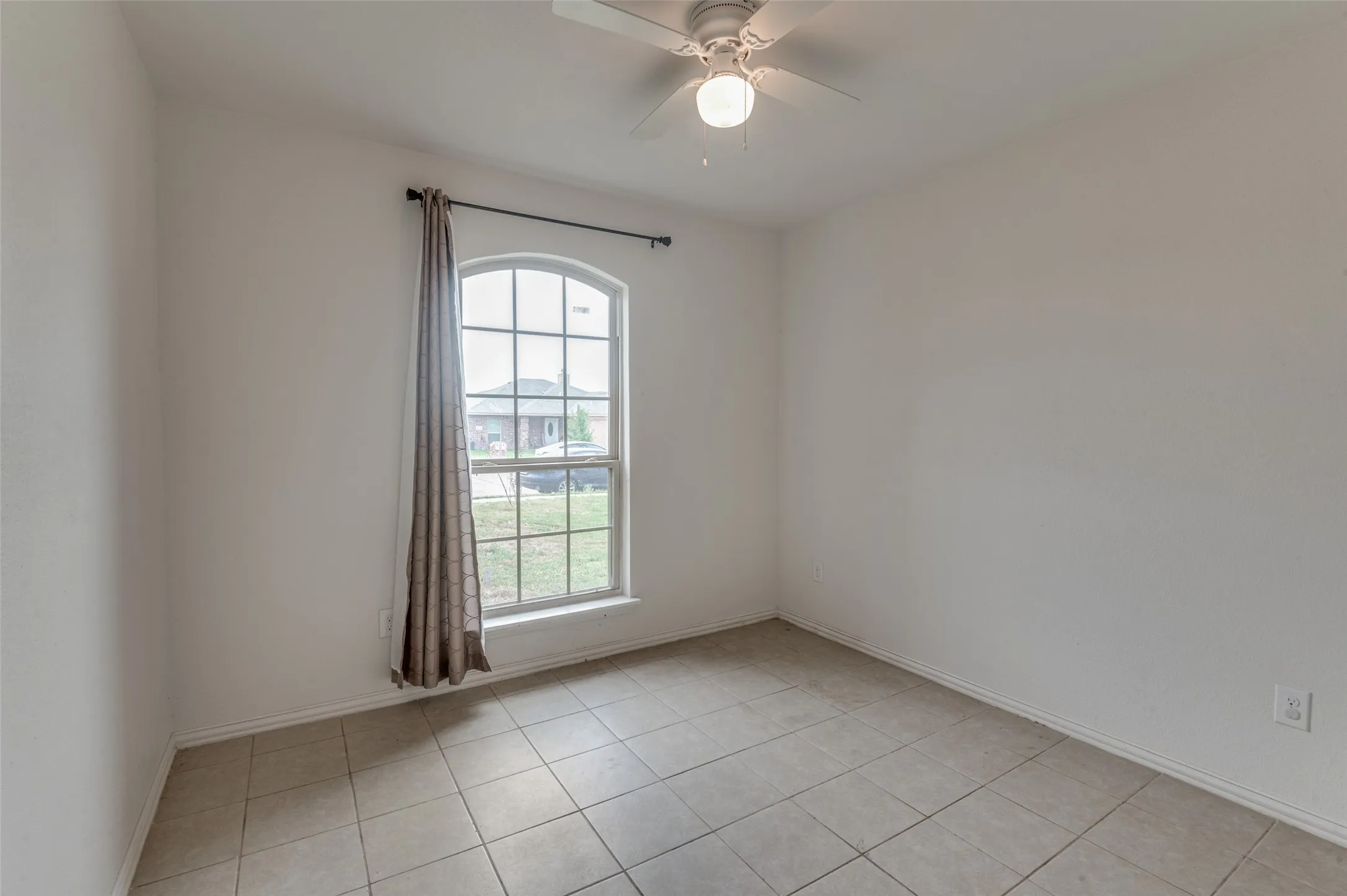 Room featuring an arched window, ceiling fan with integrated lighting, and neutral tile flooring