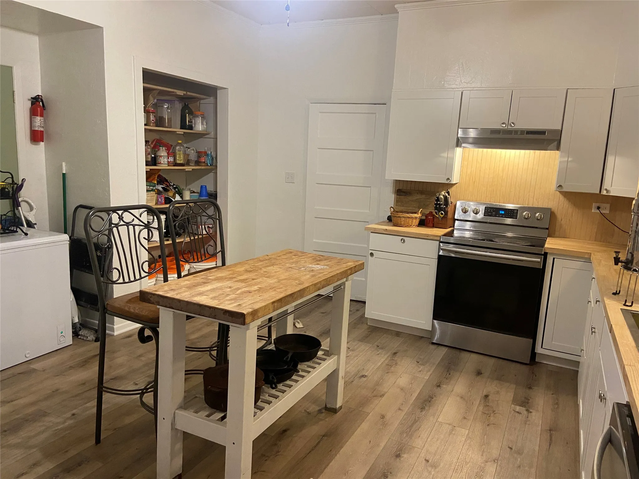 Kitchen featuring wood-finish flooring, white cabinetry, wood countertops, and a stainless steel range
