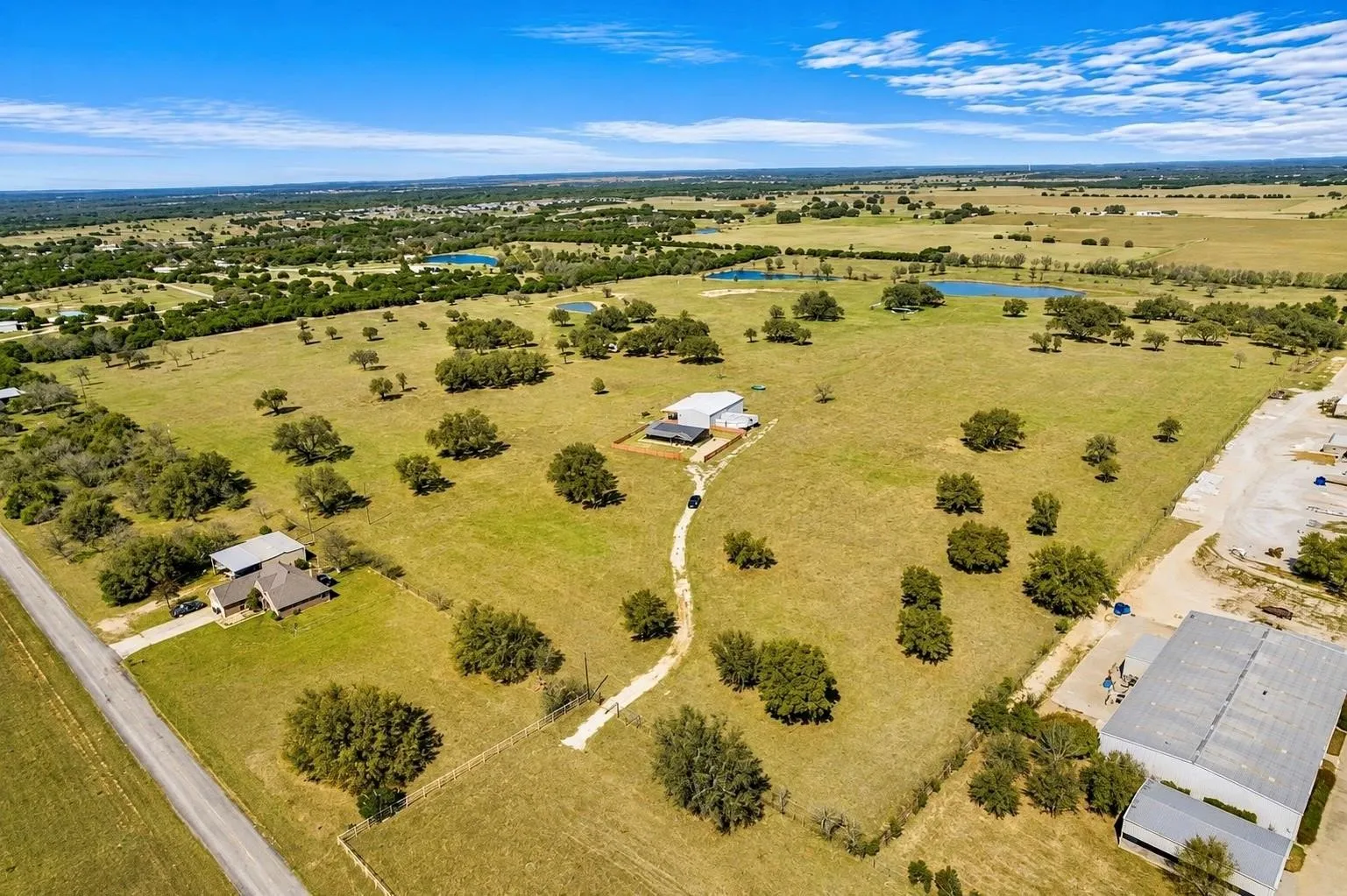 Expansive acreage featuring multiple structures, mature trees, and natural water features