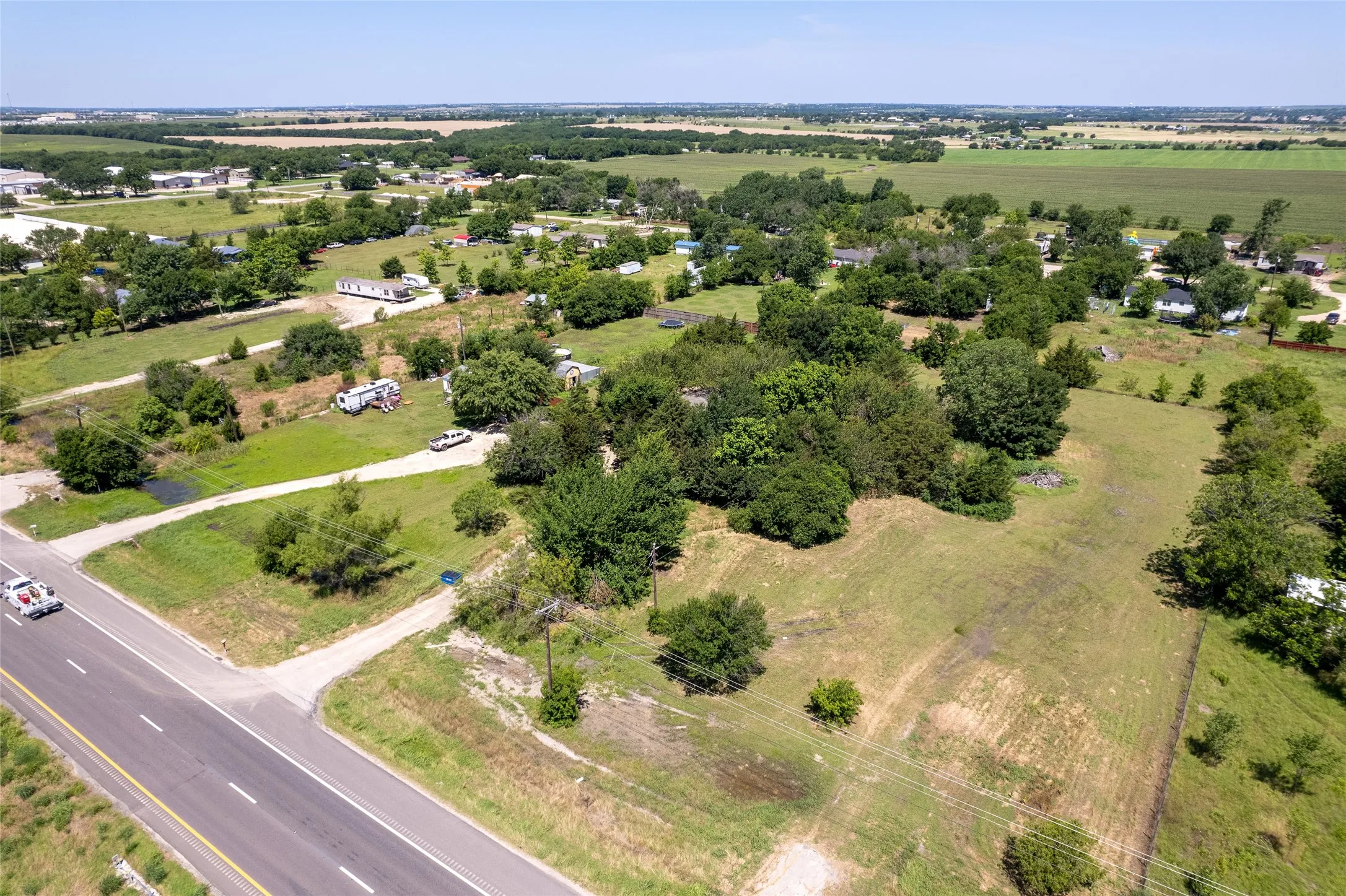 Expansive rural land with established trees and visible road frontage