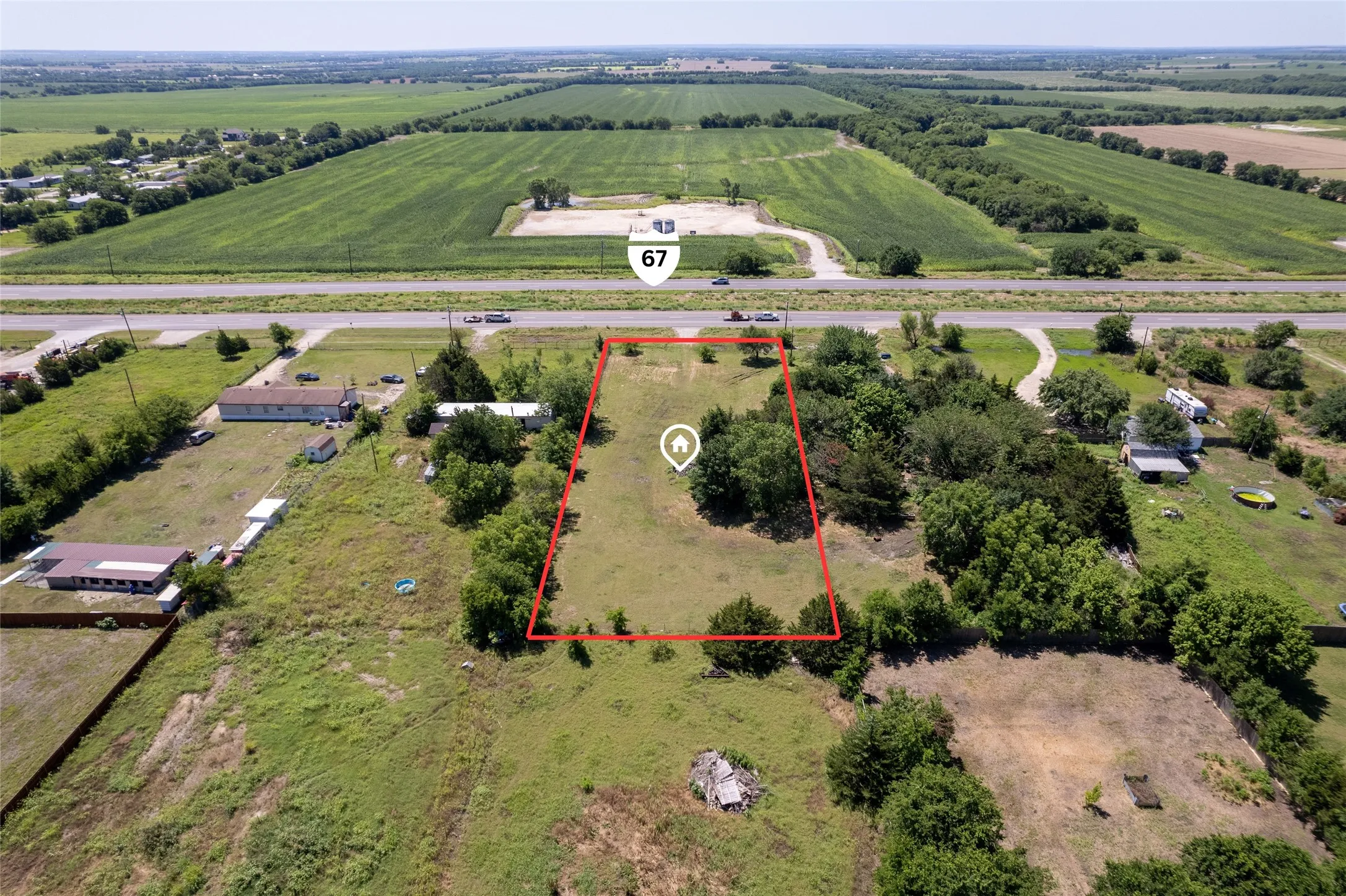 Expansive land parcel featuring clear boundaries, mature trees, and direct frontage to Highway 67