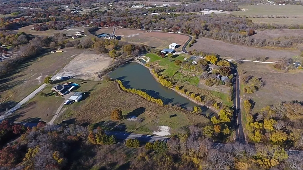 Expansive property featuring a central pond, multiple residential structures, and extensive cleared land