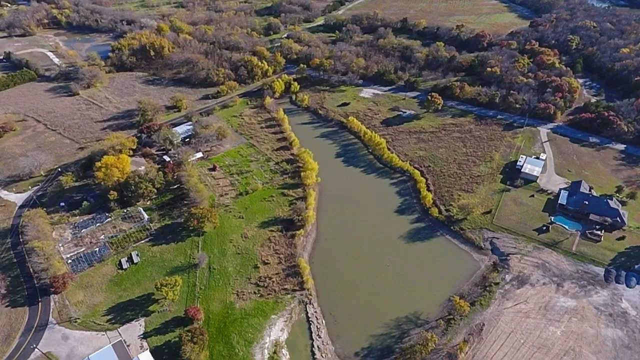 Aerial landscape featuring a large body of water, extensive natural areas, and a paved road