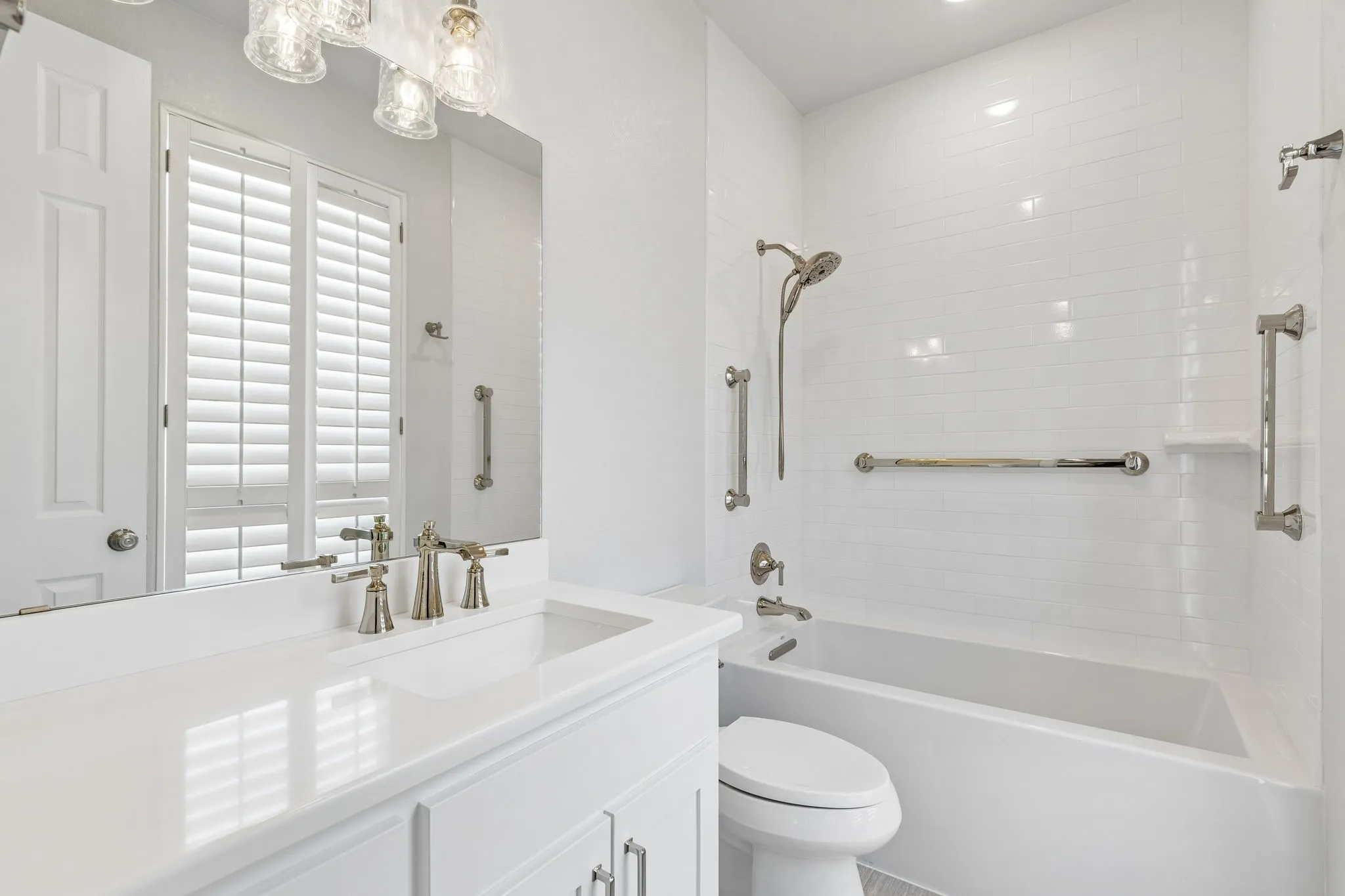 The en-euite bath features a clean, light-filled design with plantation shutters and a soaking tub with shower. Fixtures in a champagne finish—subtly blending silver and gold—add a refined, designer touch.