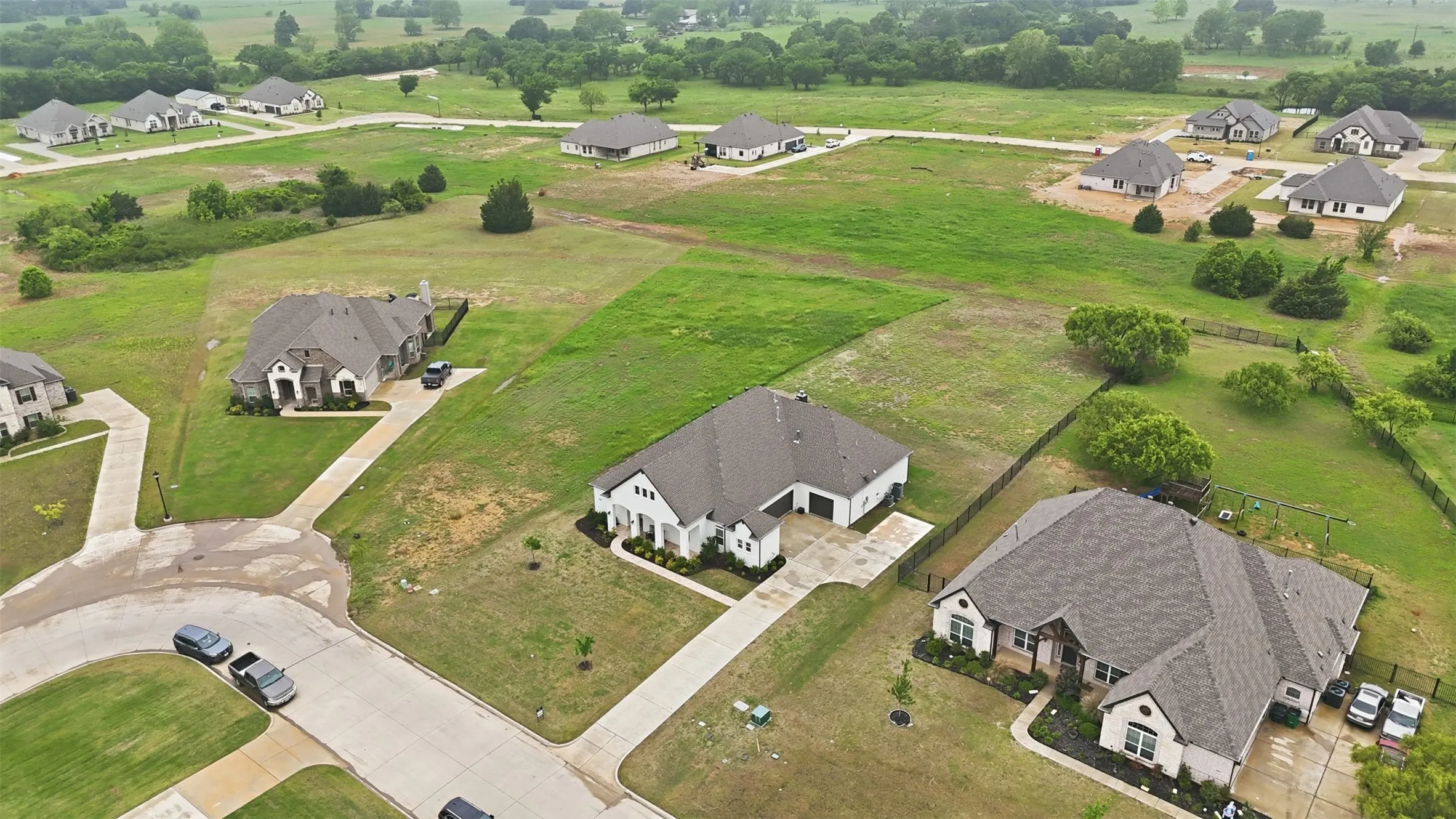 Expansive residential development with multiple single-story homes featuring attached garages, paved driveways, and manicured front landscaping