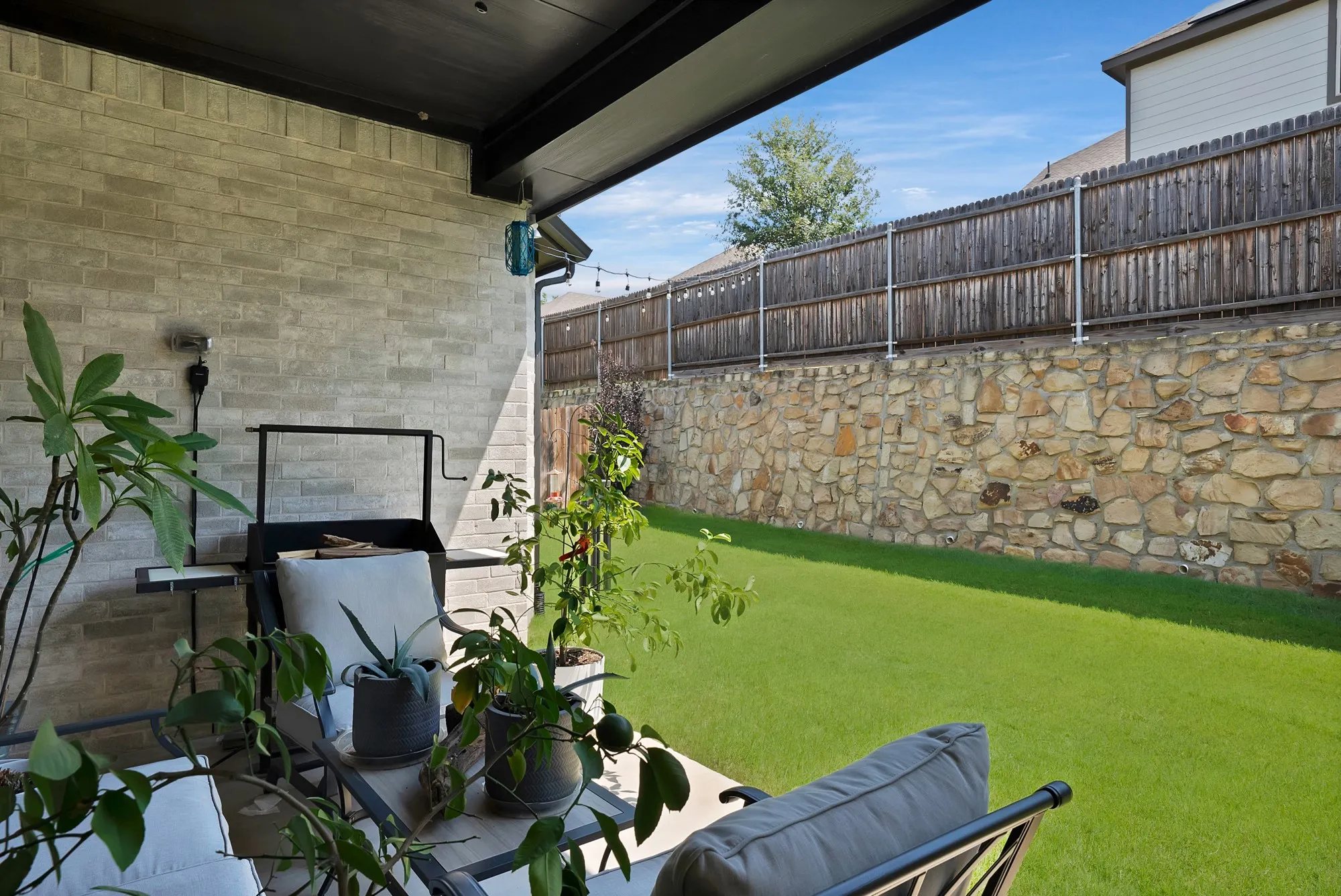 This property features a covered patio with a light gray brick wall and a well-maintained lawn
