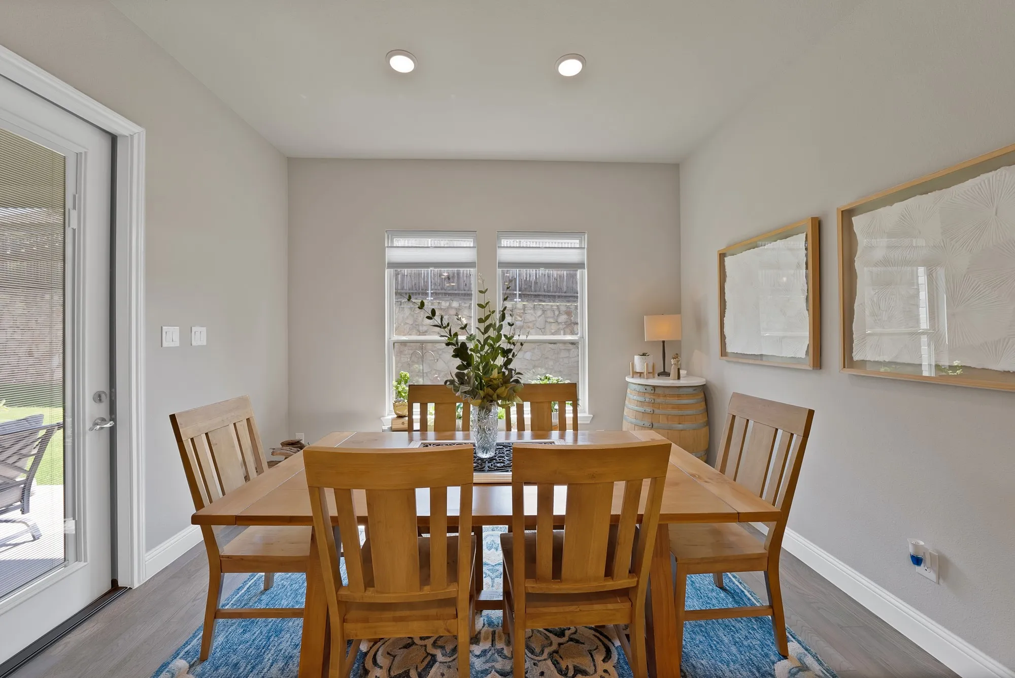 Dining area with light-colored walls, recessed lighting, and a glass-paneled door leading to an outdoor space