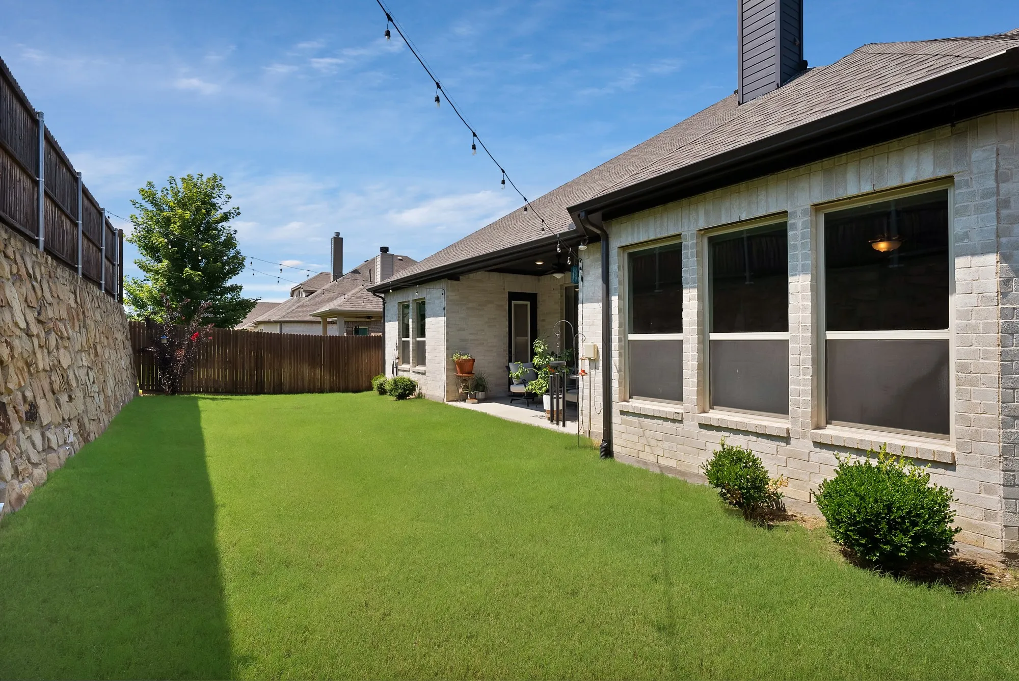 The property features a spacious backyard with a well-maintained lawn and a stone retaining wall