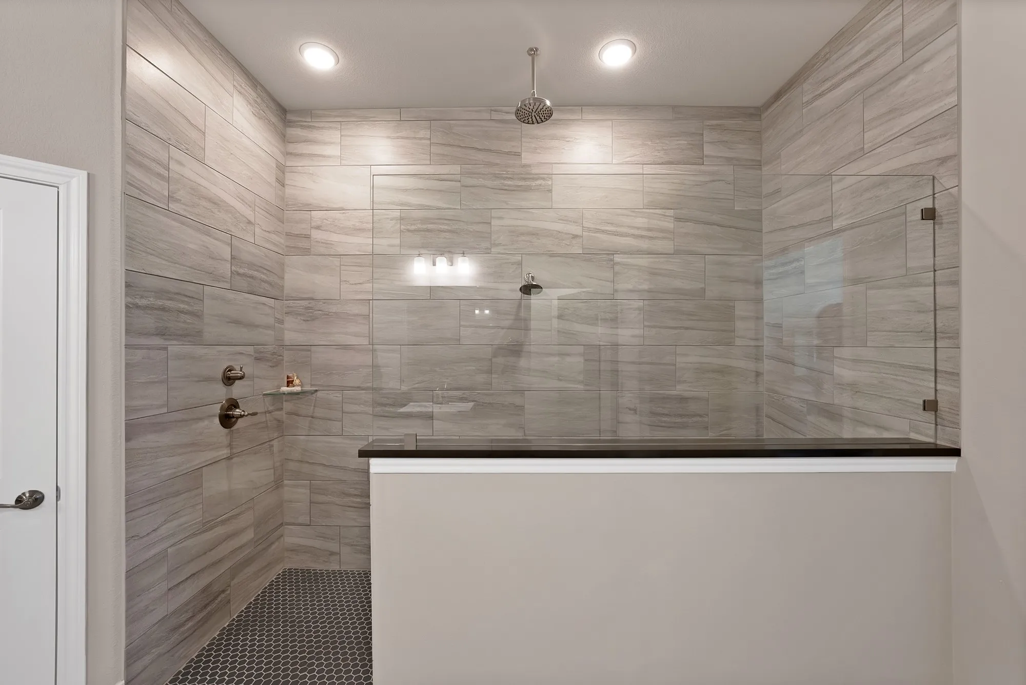 The property features a spacious shower with light-toned rectangular wall tiles and a dark hexagonal floor tile