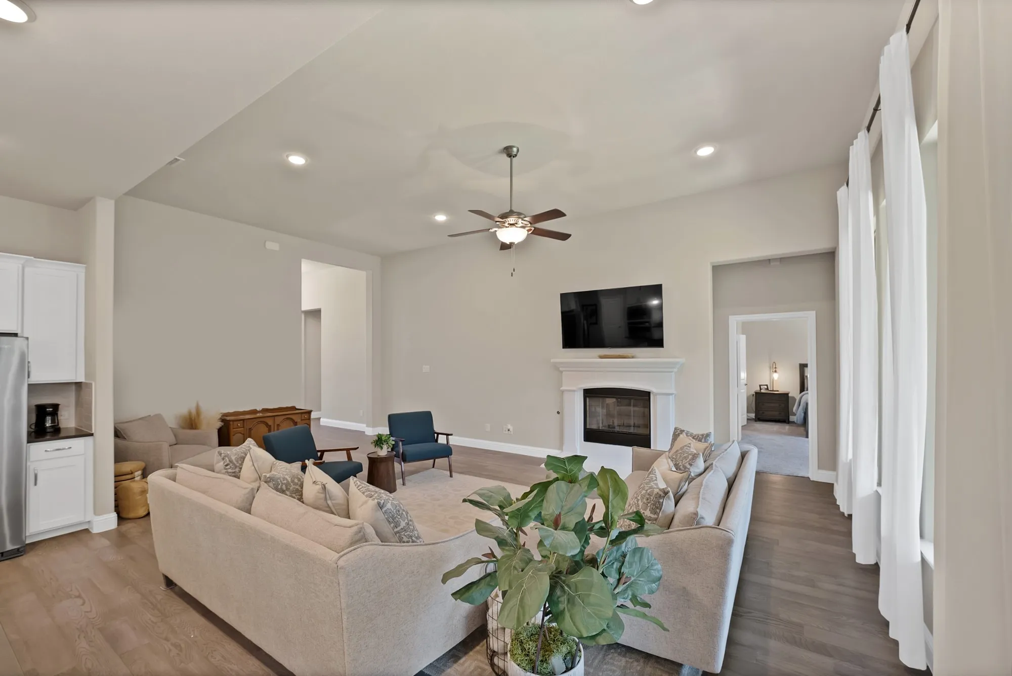 The living area features hardwood floors, a ceiling fan, recessed lighting, and a fireplace with a white mantel