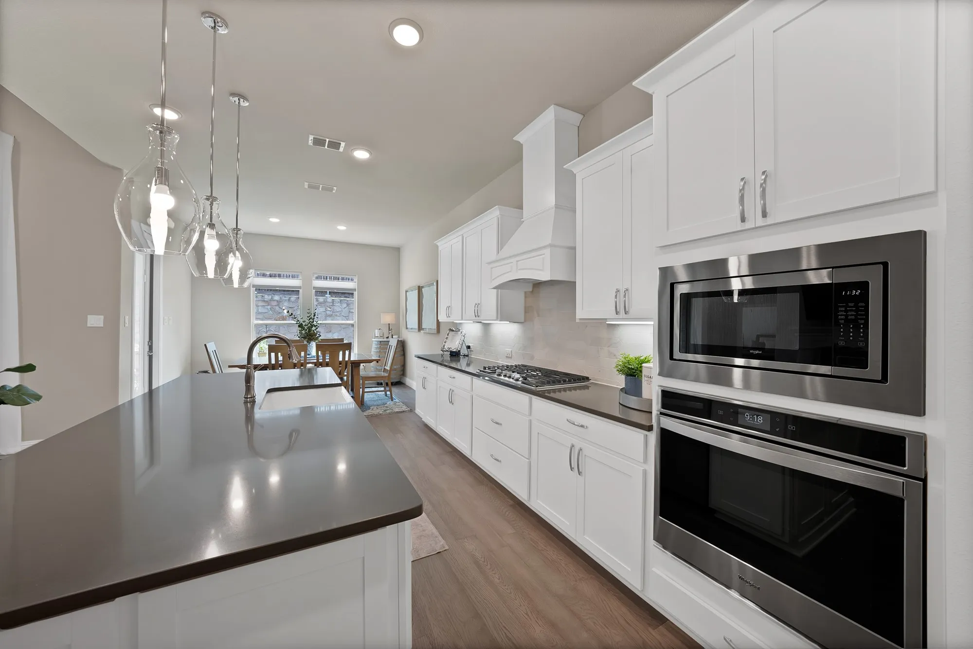 The kitchen features white cabinetry, dark countertops, and stainless steel appliances, including a built-in microwave and oven