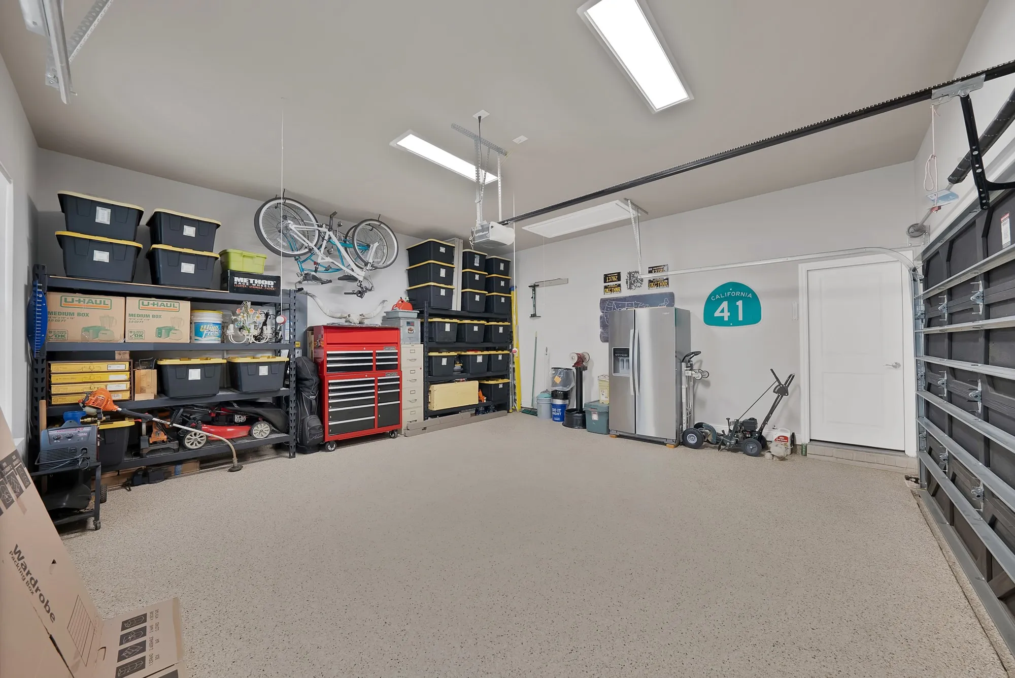 The garage features a coated floor, overhead lighting, and a white door