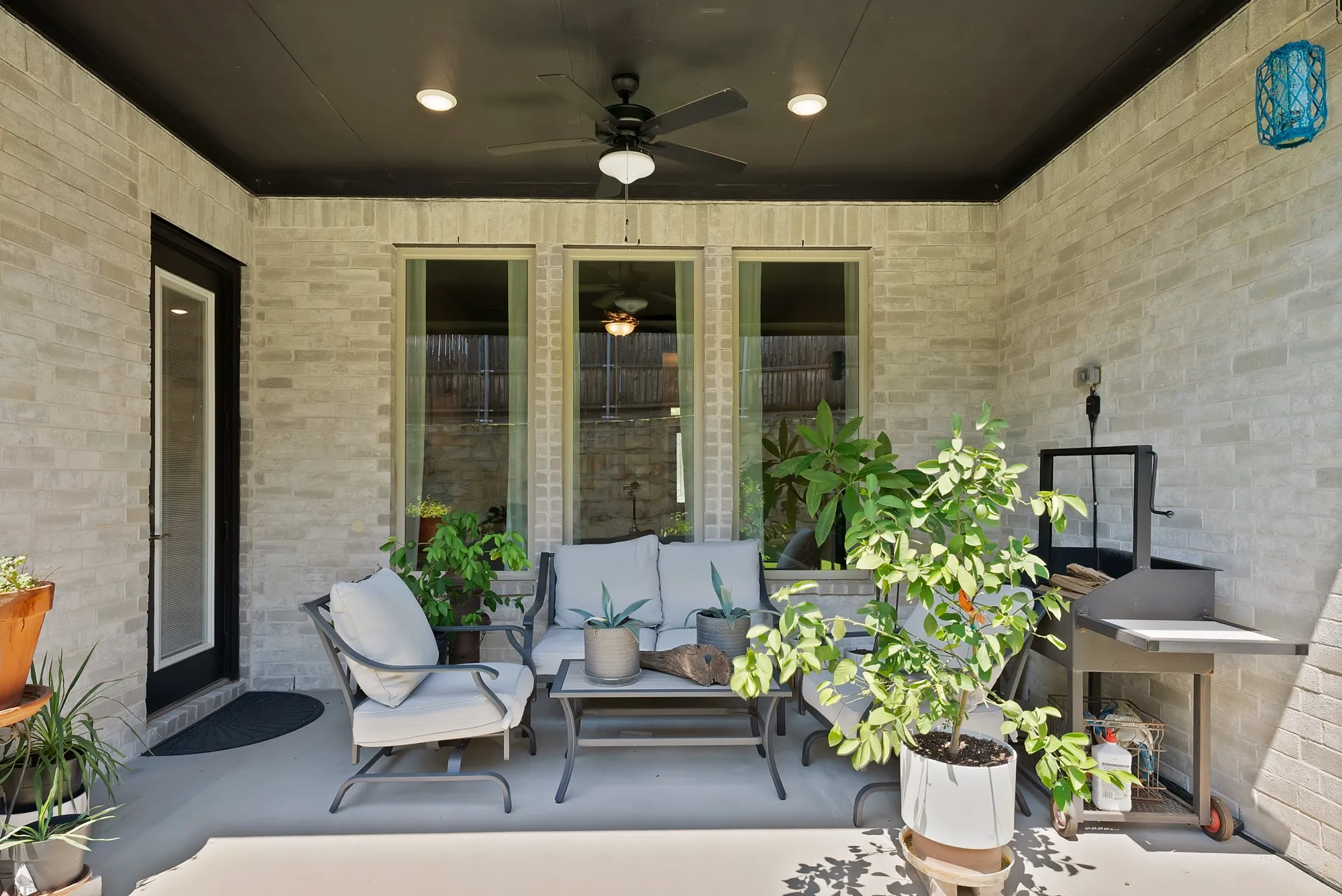 The property features a covered patio with a ceiling fan, recessed lighting, and a light-colored brick exterior