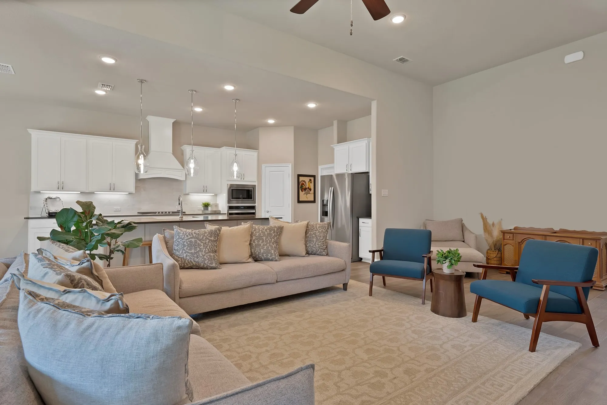 Open concept living area featuring a kitchen with white cabinetry and stainless steel appliances, a spacious living room, and high ceilings with recessed lighting