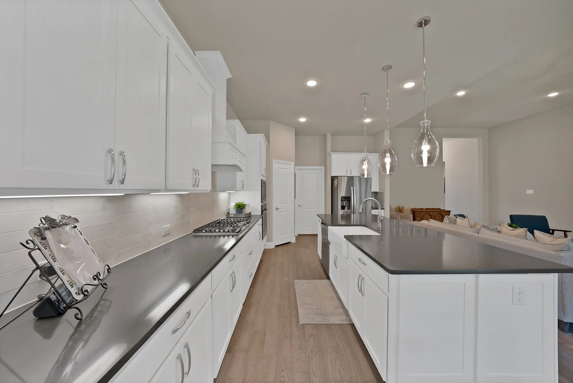 The kitchen features white cabinetry, dark countertops, and a gas range