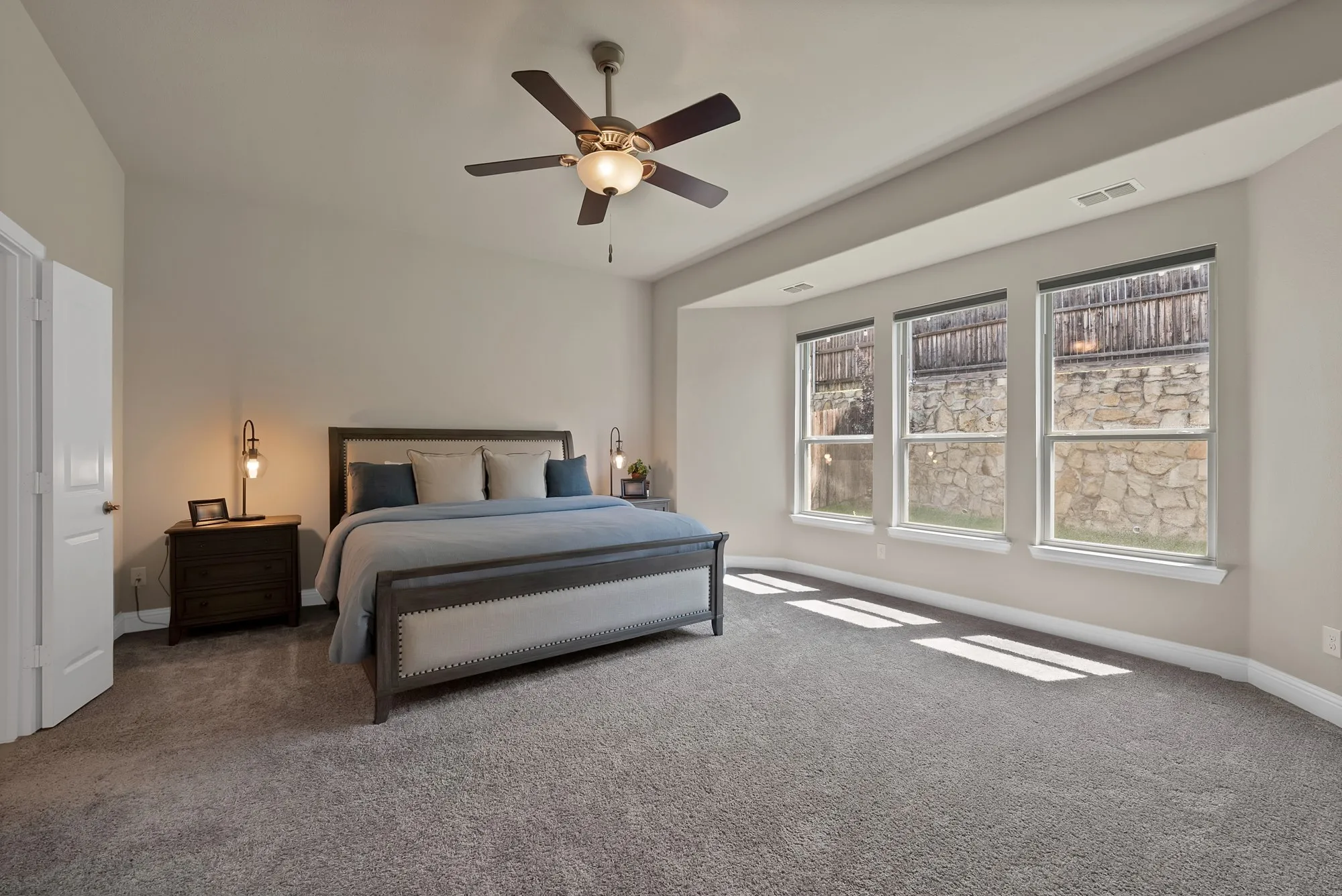 The room features a vaulted ceiling, a ceiling fan, and carpeted flooring