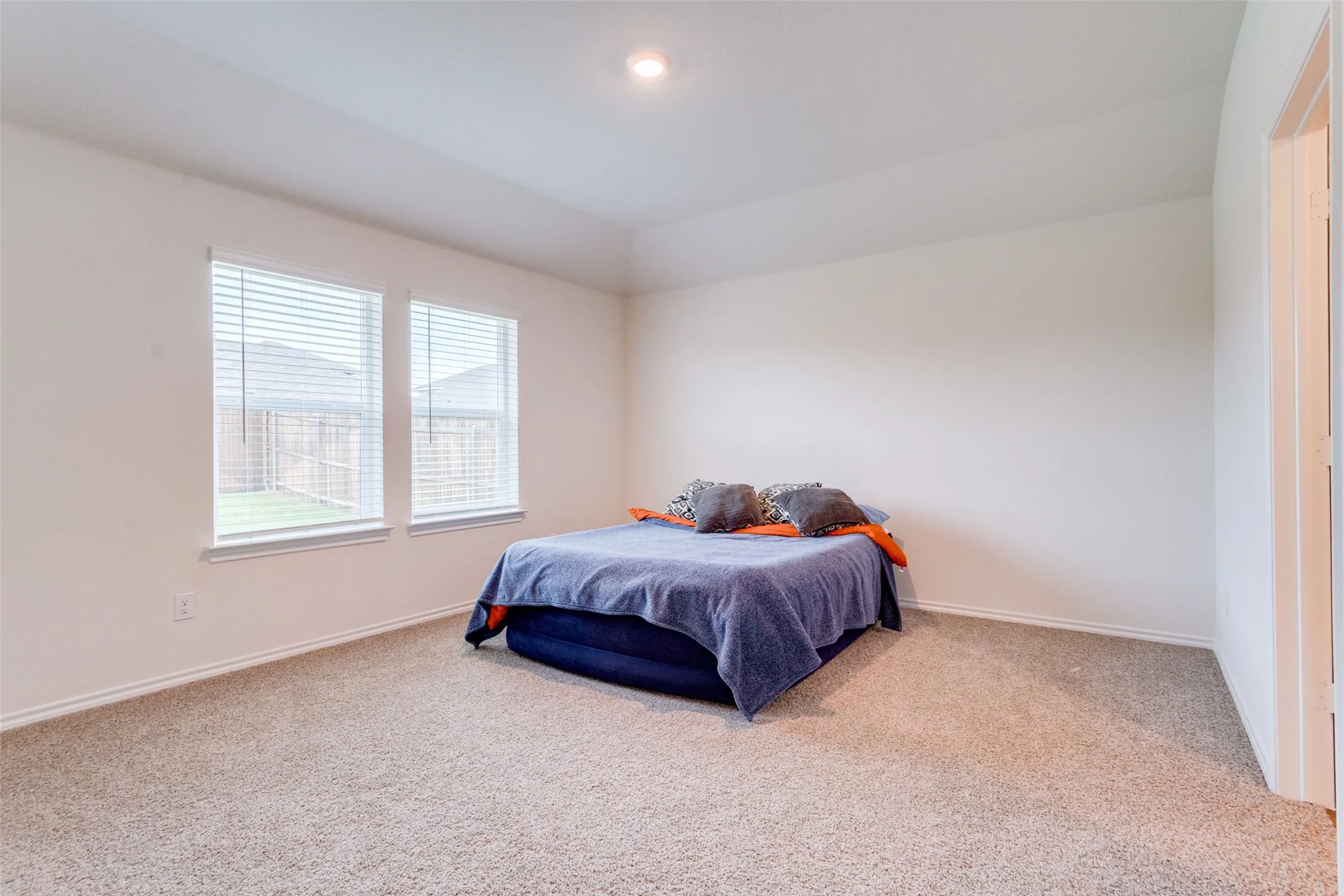 Spacious room featuring neutral carpeting, white walls, and a tray ceiling with recessed lighting