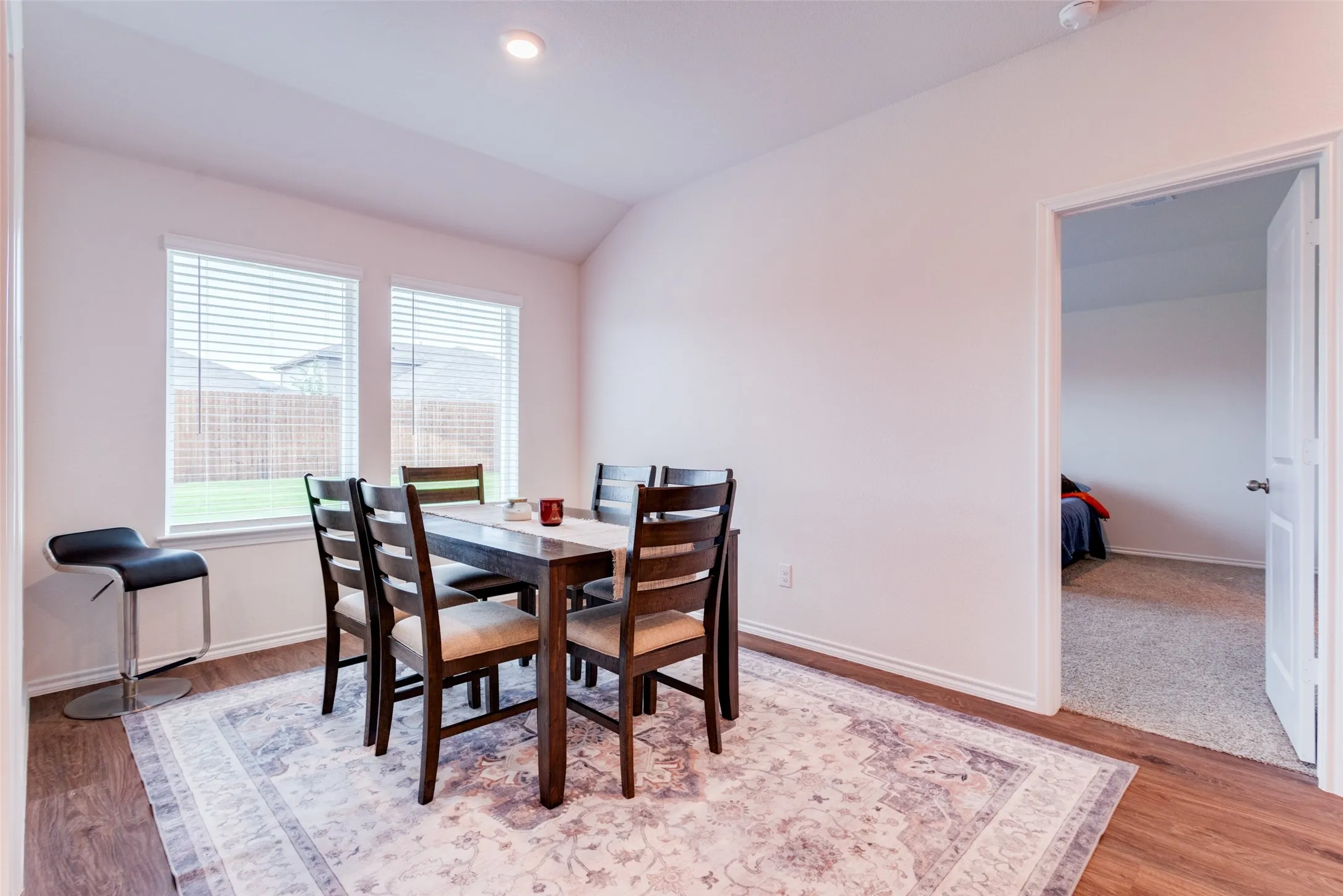 Dining area featuring wood-finish flooring, two large windows with blinds, recessed lighting, and a neutral color palette