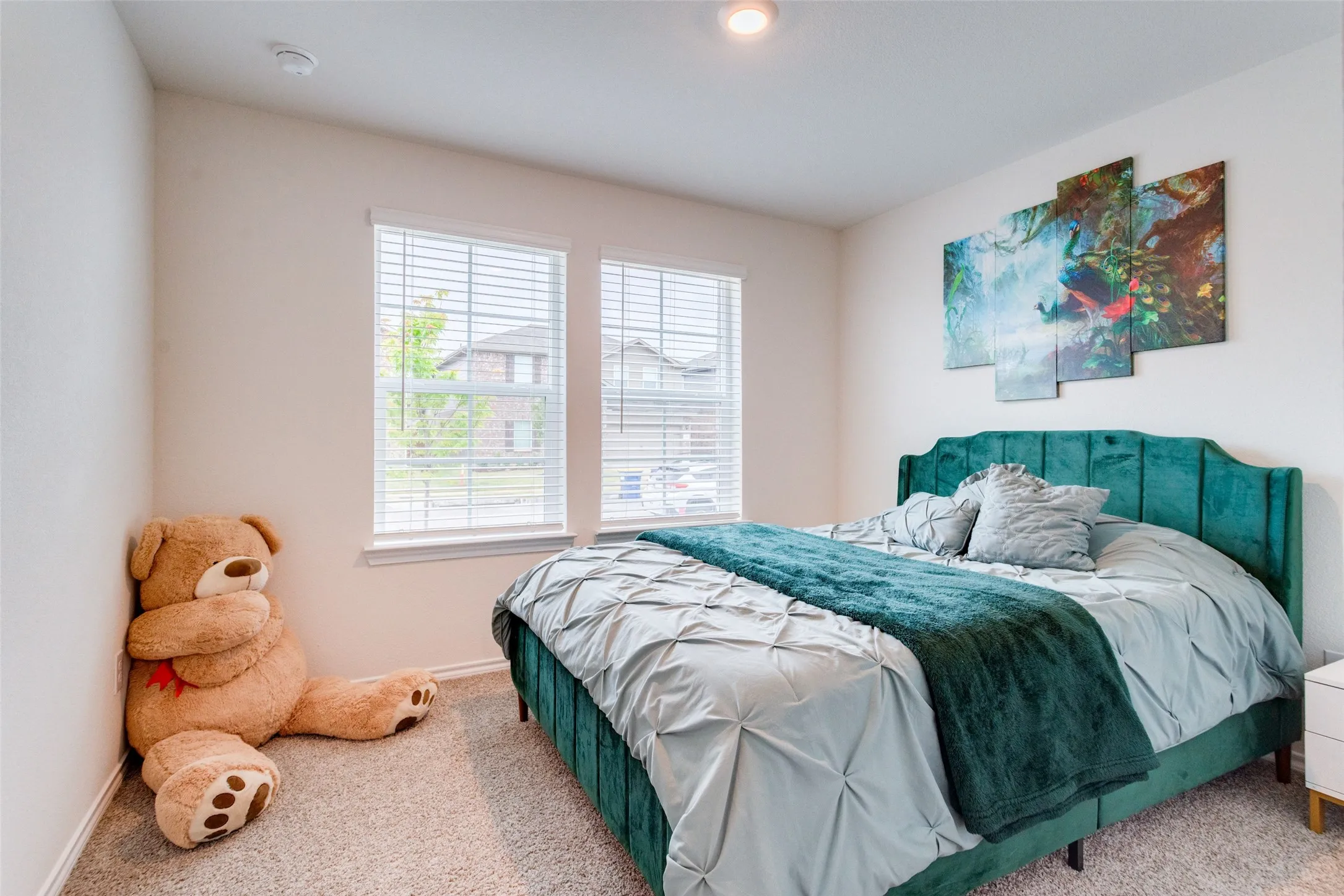 Carpeted bedroom with two windows, featuring light-colored walls and a recessed ceiling light