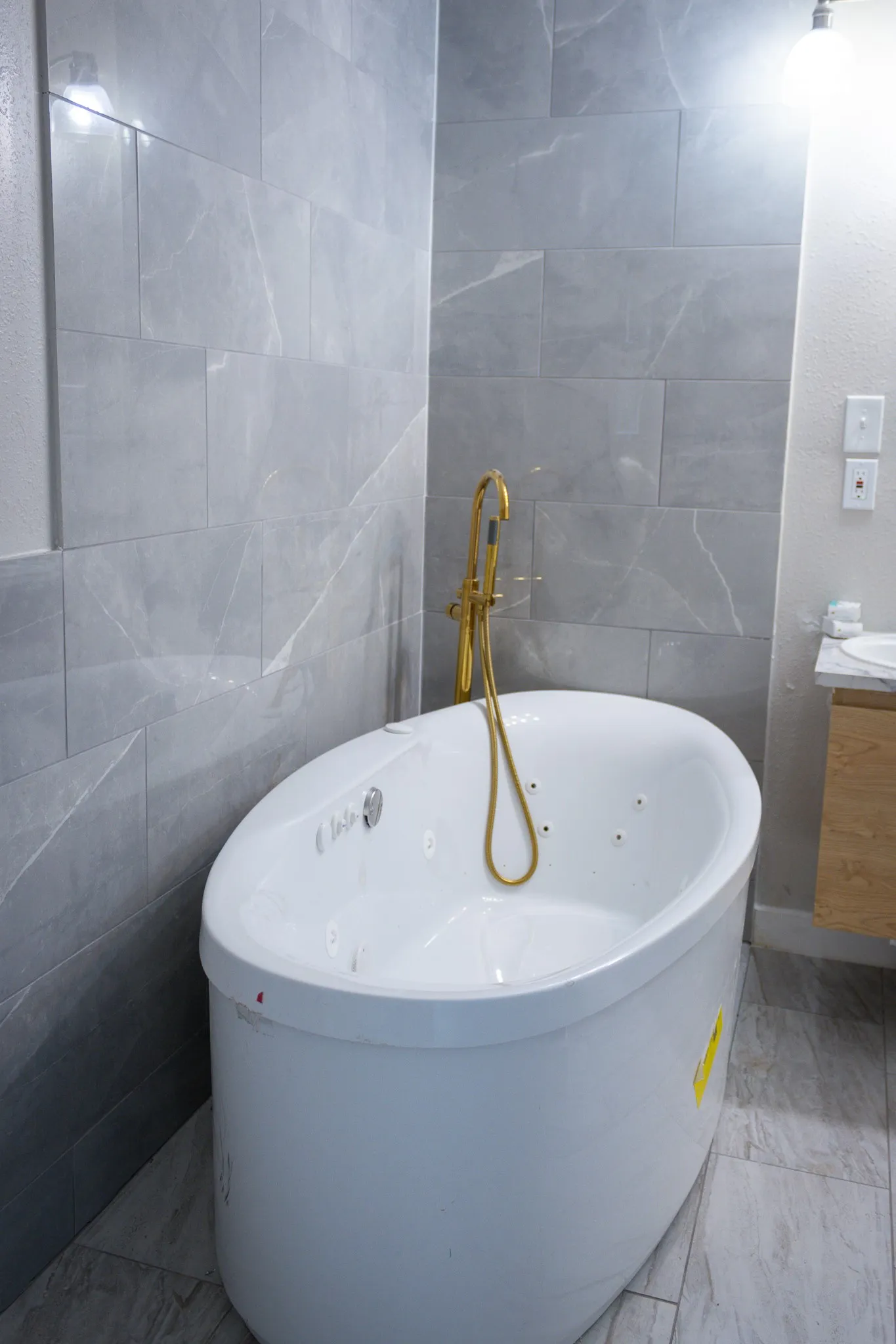 Full bathroom with tile walls, a whirlpool tub, vanity, and marble look tile flooring