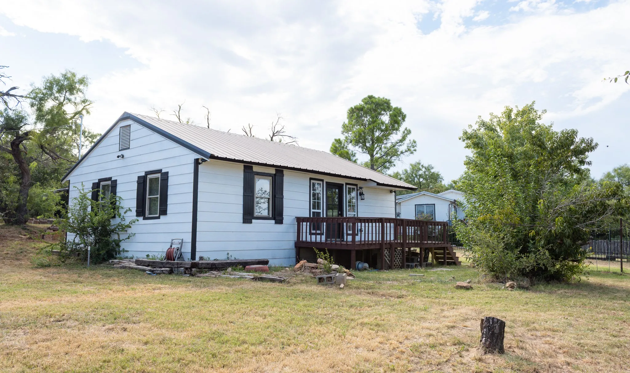 View of front of property featuring a wooden deck, a front lawn, and a metal roof