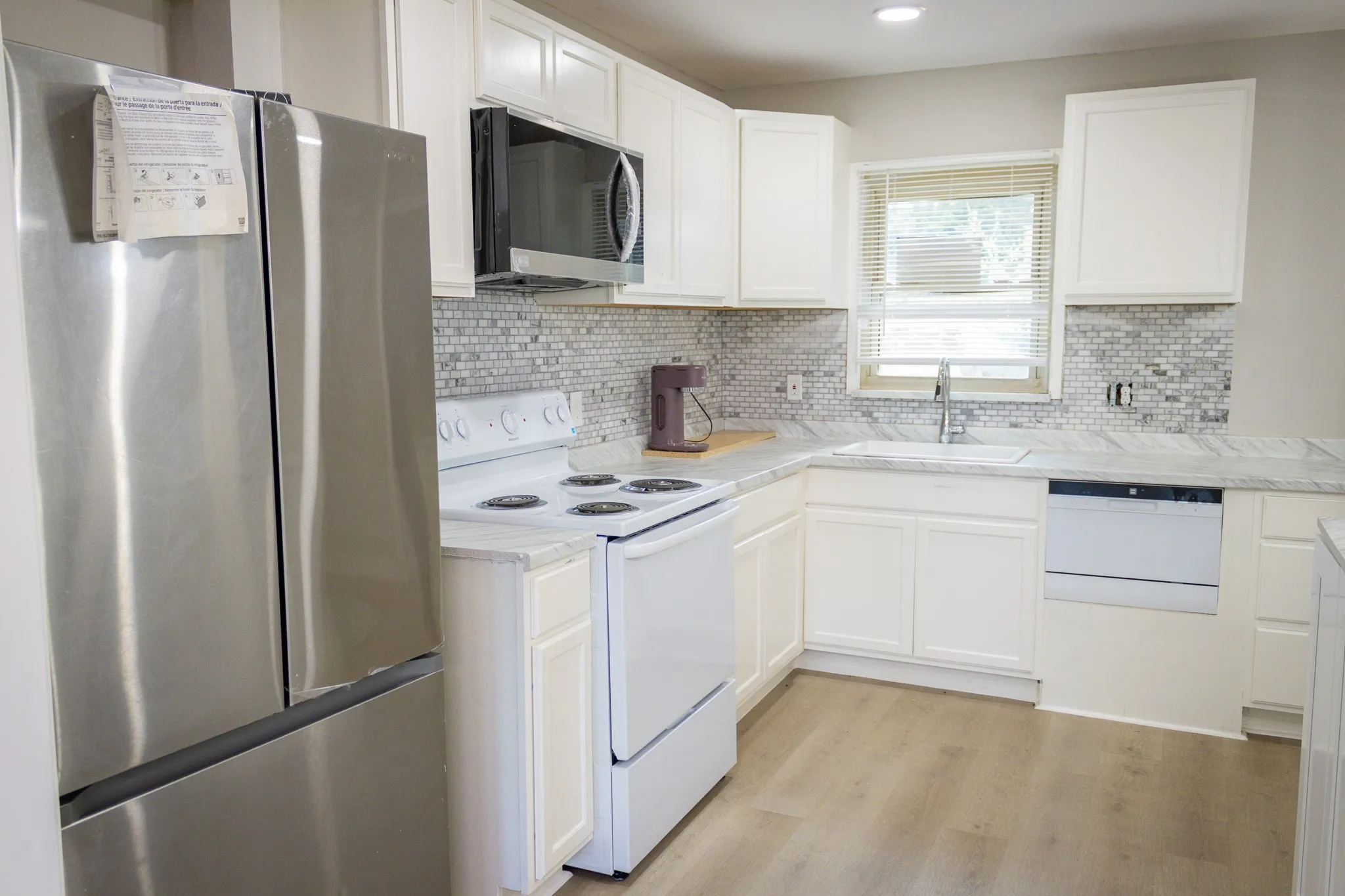 Kitchen with white appliances, light wood-style flooring, white cabinetry, tasteful backsplash, and recessed lighting