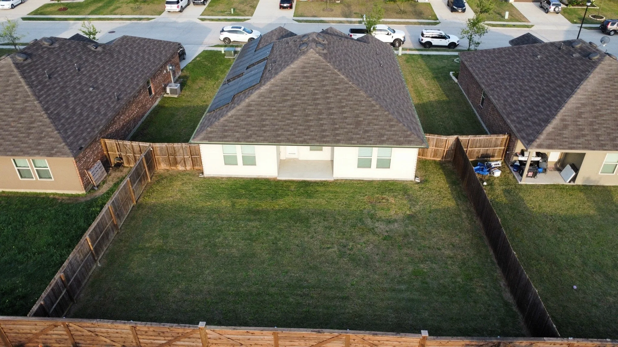 Expansive backyard featuring a manicured lawn, a full wood privacy fence, and a concrete patio