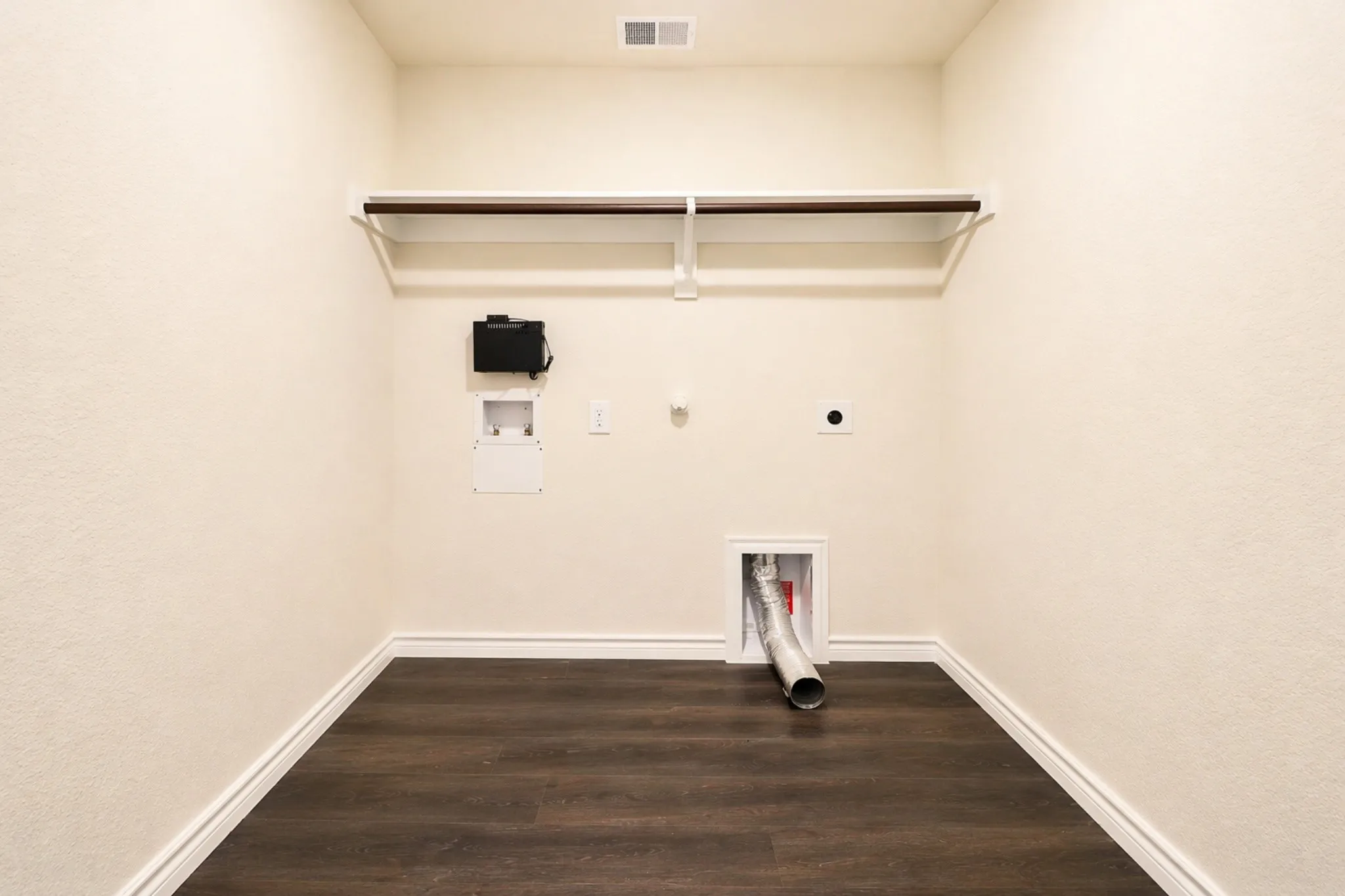 Dedicated utility space featuring wood-finish flooring, light-toned walls, and white trim